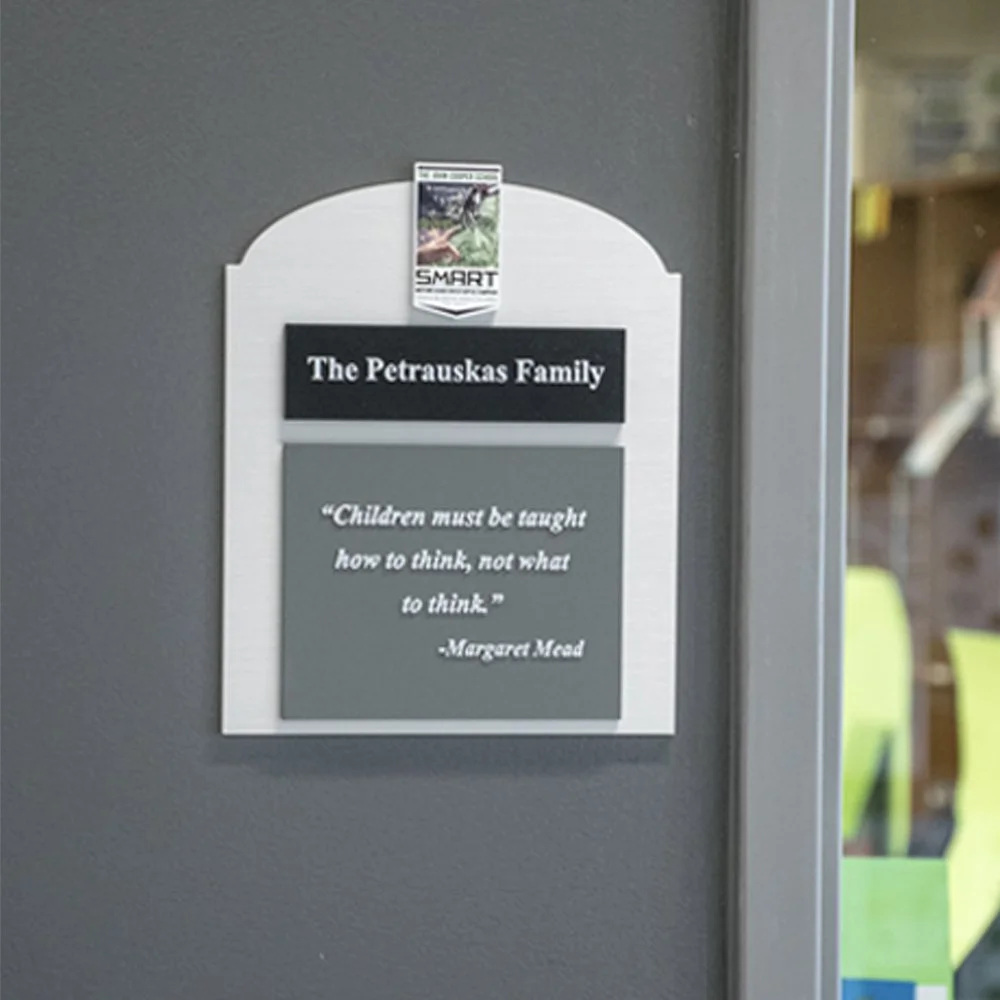 Custom ADA donor recognition signage for The Petruskas Family featuring tactile lettering and decorative framed design at The John Cooper School.