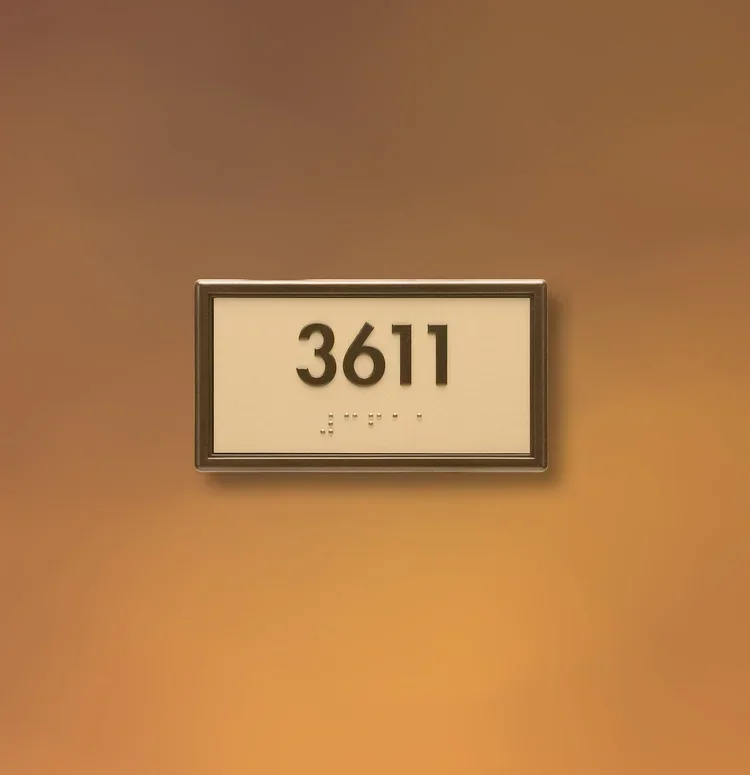 Framed ADA room number sign showing 3611 with raised numbers and Braille, Houston building interior.