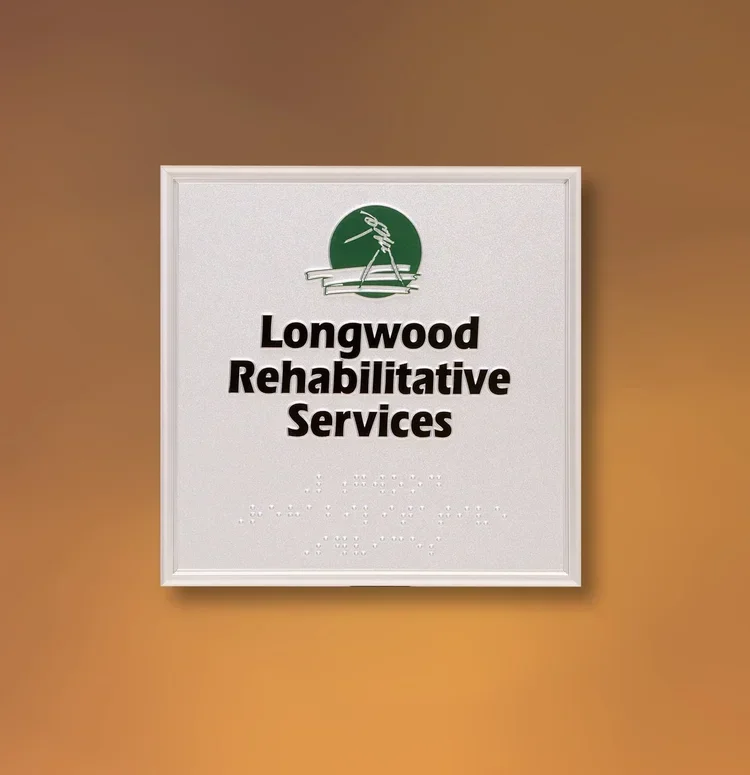 Framed ADA sign for Longwood Rehabilitative Services with raised tactile lettering, braille, and white frame, professional healthcare signage in Houston.