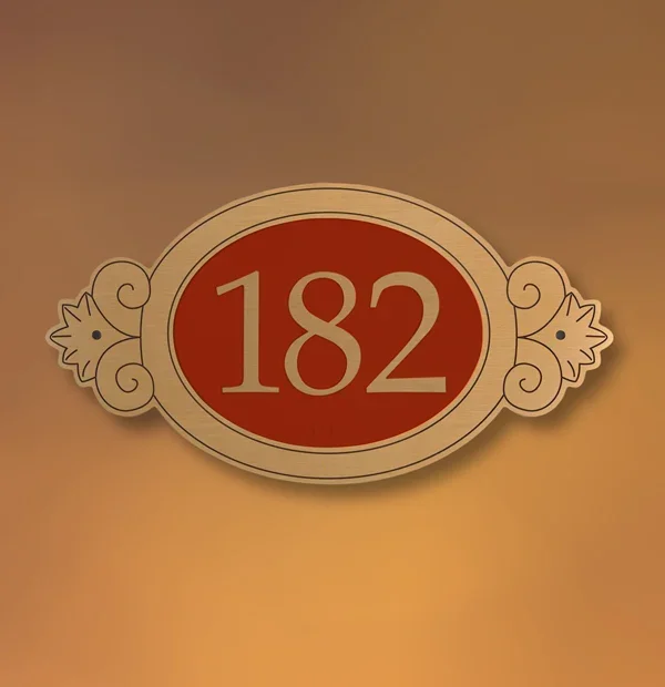 Decorative metal ADA room sign with ornate frame and raised number 182, classic red and gold finish for elegant interiors in Houston.