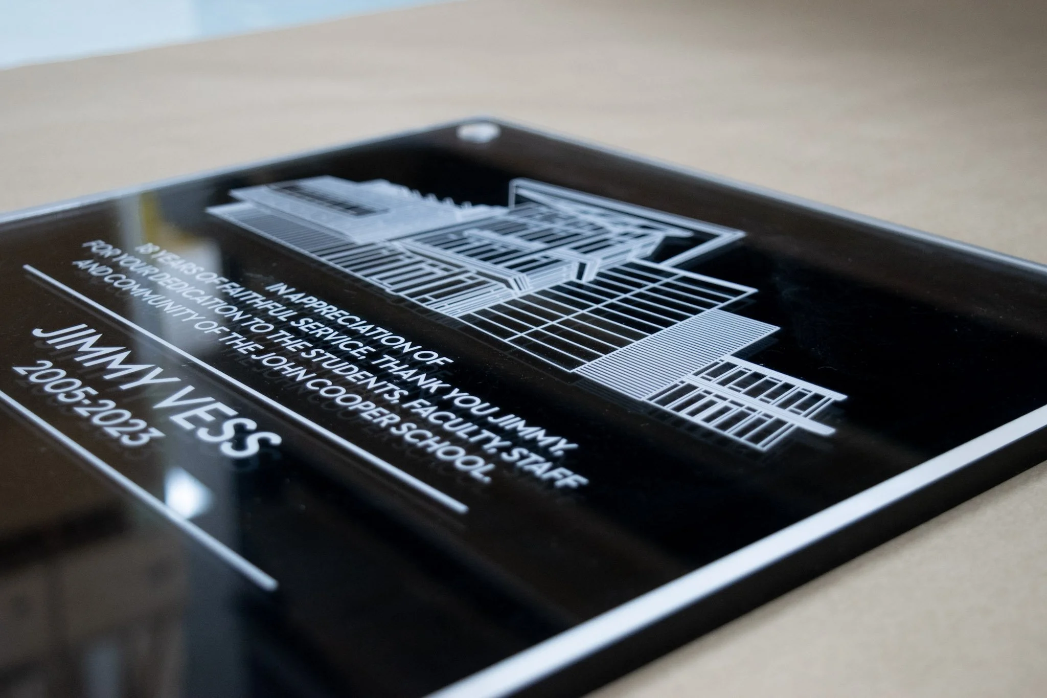 Custom glass recognition plaque honoring Jimmy Vess, featuring etched text and an architectural illustration for The John Cooper School.