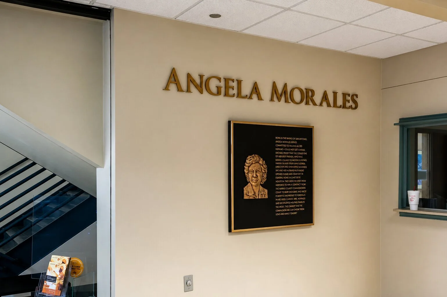 Bronze recognition plaque with relief portrait and dimensional lettering honoring Angela Morales installed on an interior HCC wall.