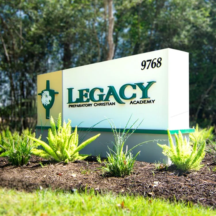 Custom illuminated monument sign for Legacy Preparatory Christian Academy surrounded by landscaped greenery in Houston area.