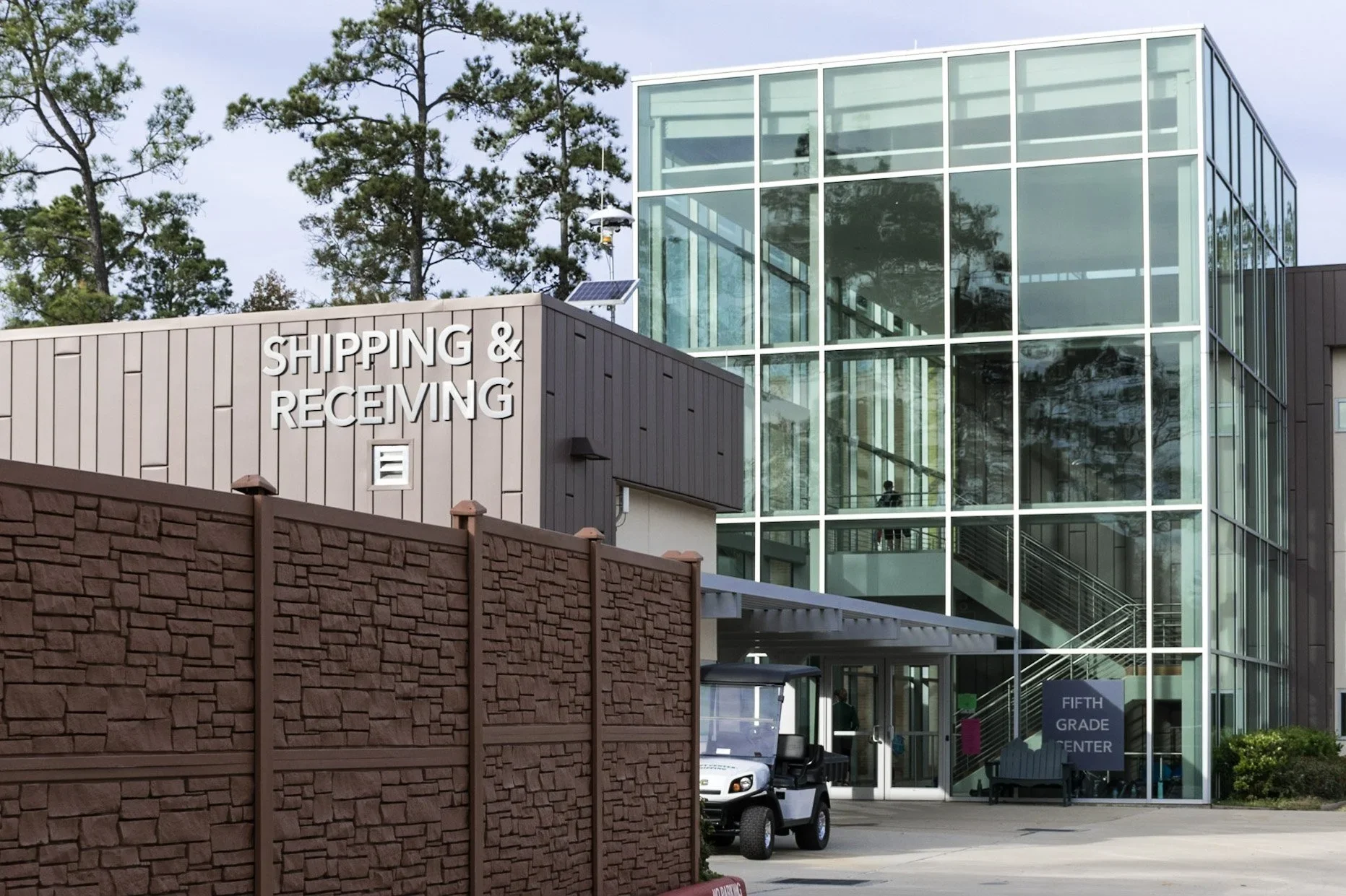 Custom dimensional metal lettering installed on modern school building exterior for shipping and receiving entrance signage.