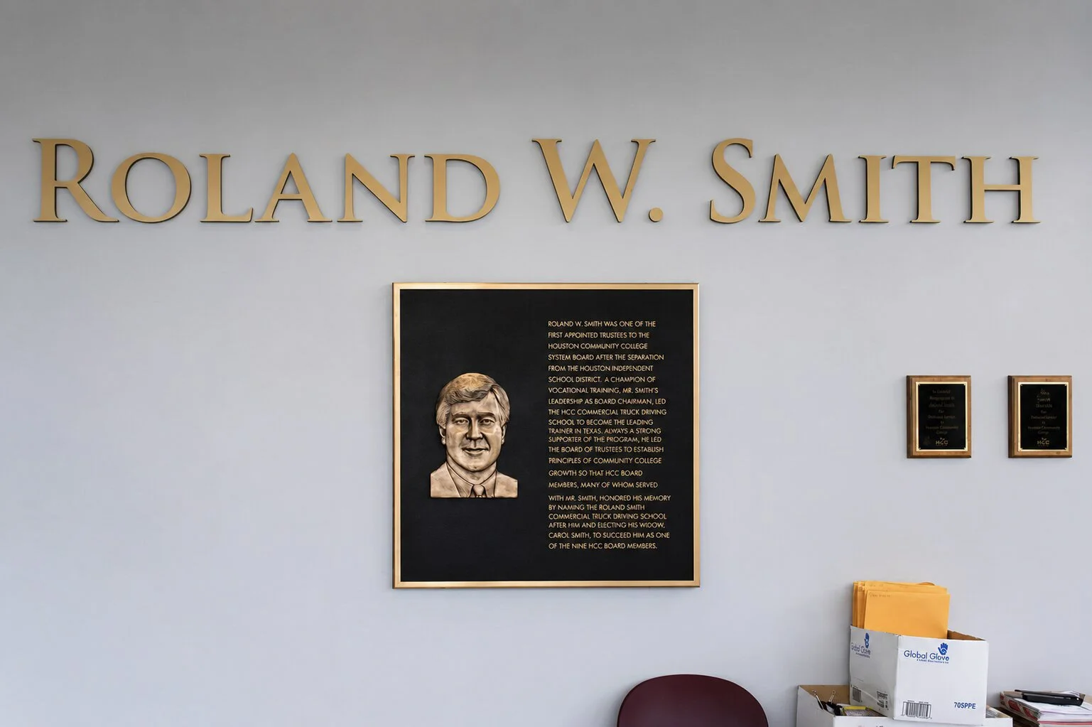 Bronze memorial plaque with a raised portrait of Roland W. Smith installed beneath dimensional lettering at Houston Community College.