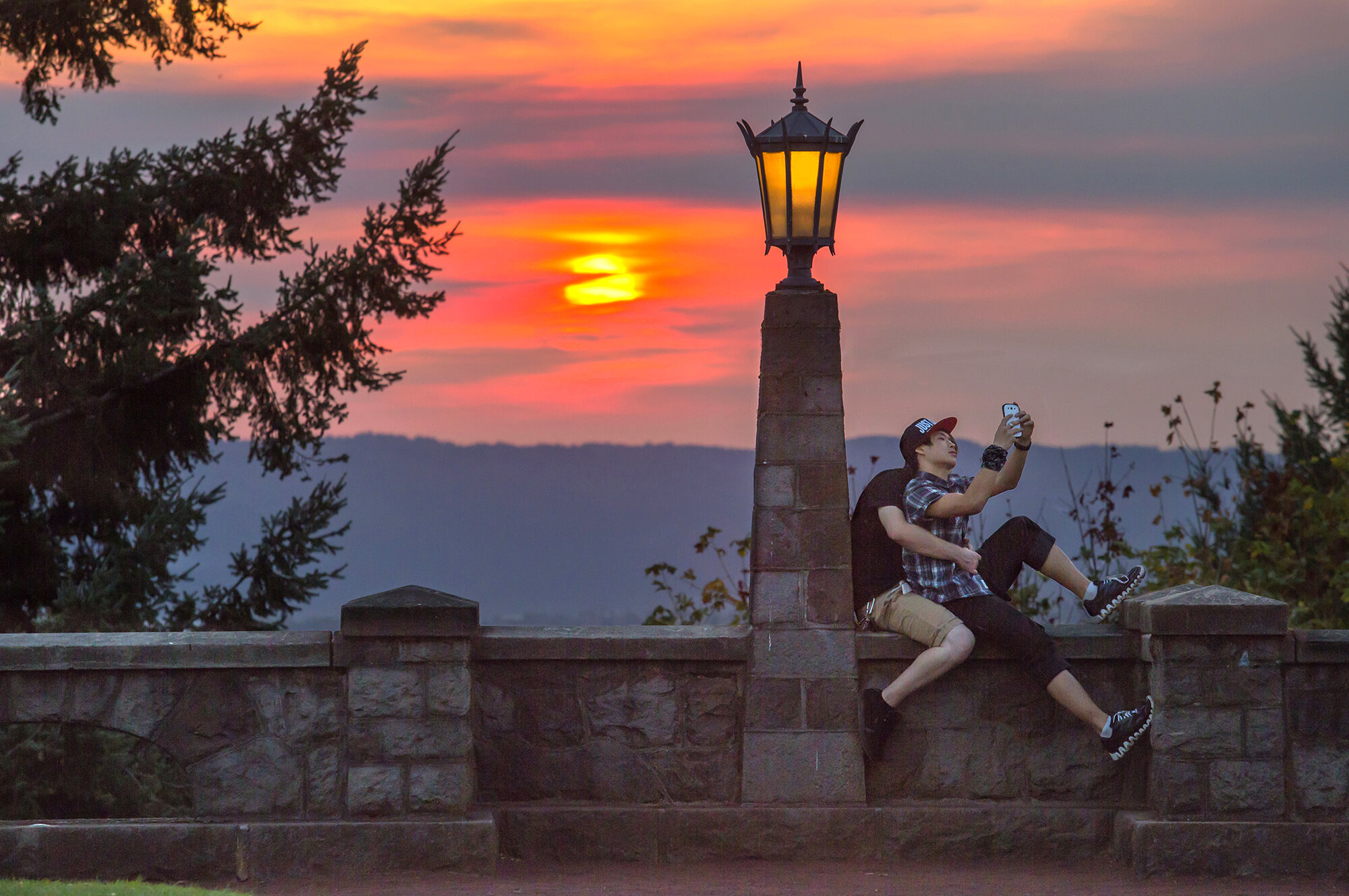 Daniel Lim and Brian Cort take a selfie at Rocky Butte Park during a smoke-filled sunset over Portland on Monday evening.