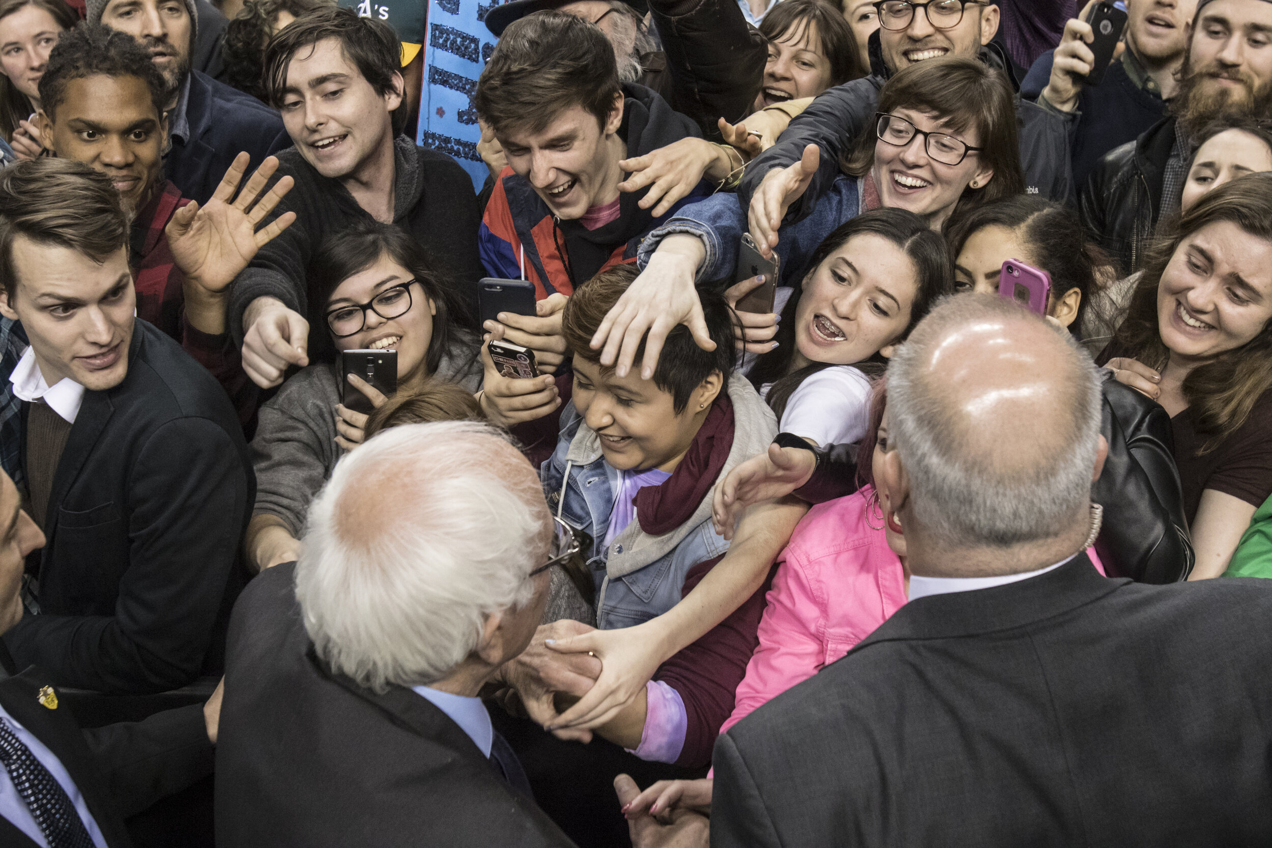Bernie Sanders supporters crowd around the presidential candidate as he leaves a rally at the Moda Center.