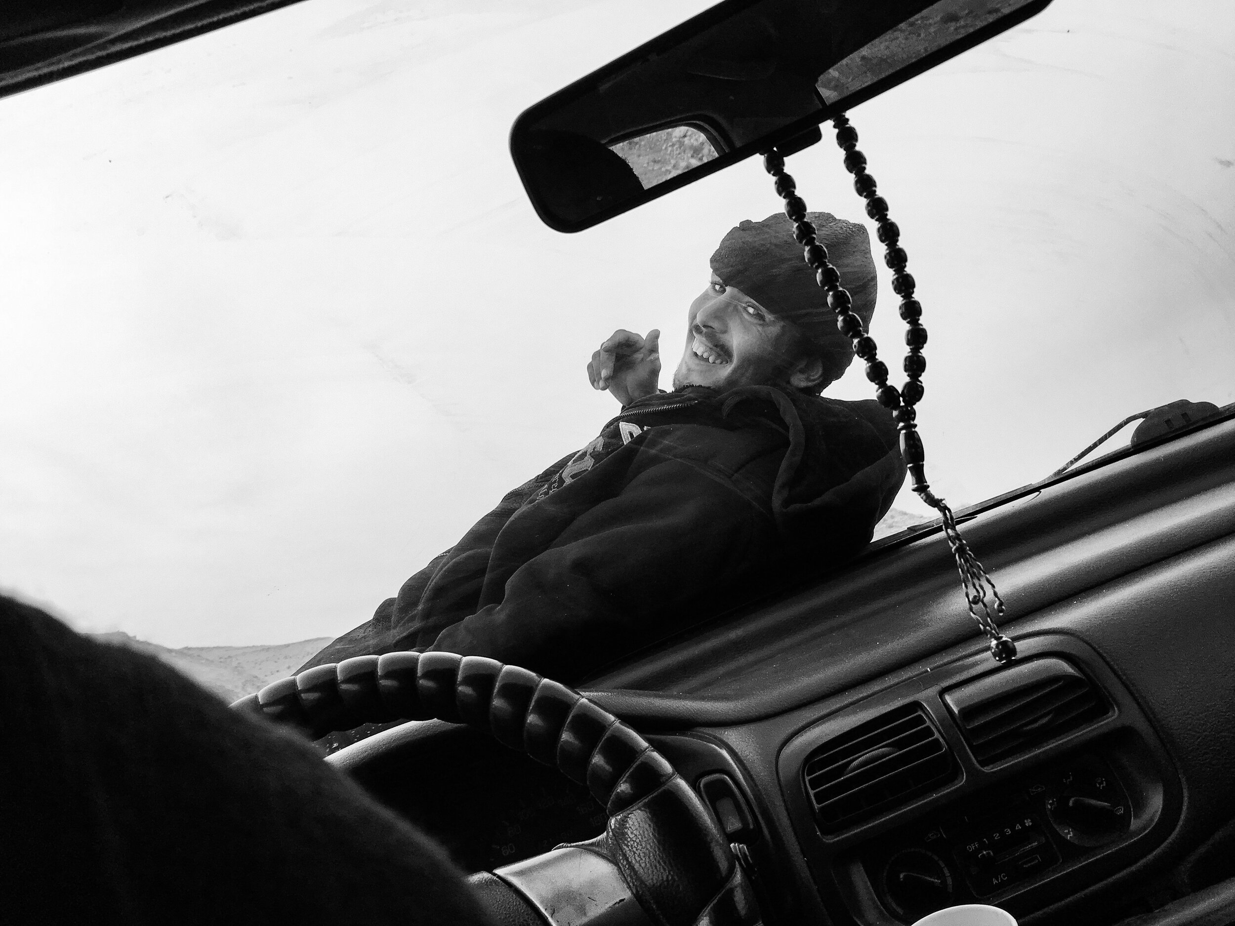  It was a day trip in the valley of a desert. On our return we hitched a ride with a local cab. I bet he was expecting us, but there were too many of us for his friend to bum a ride back as well. So instead he sat on the hood of the car. The ride wen