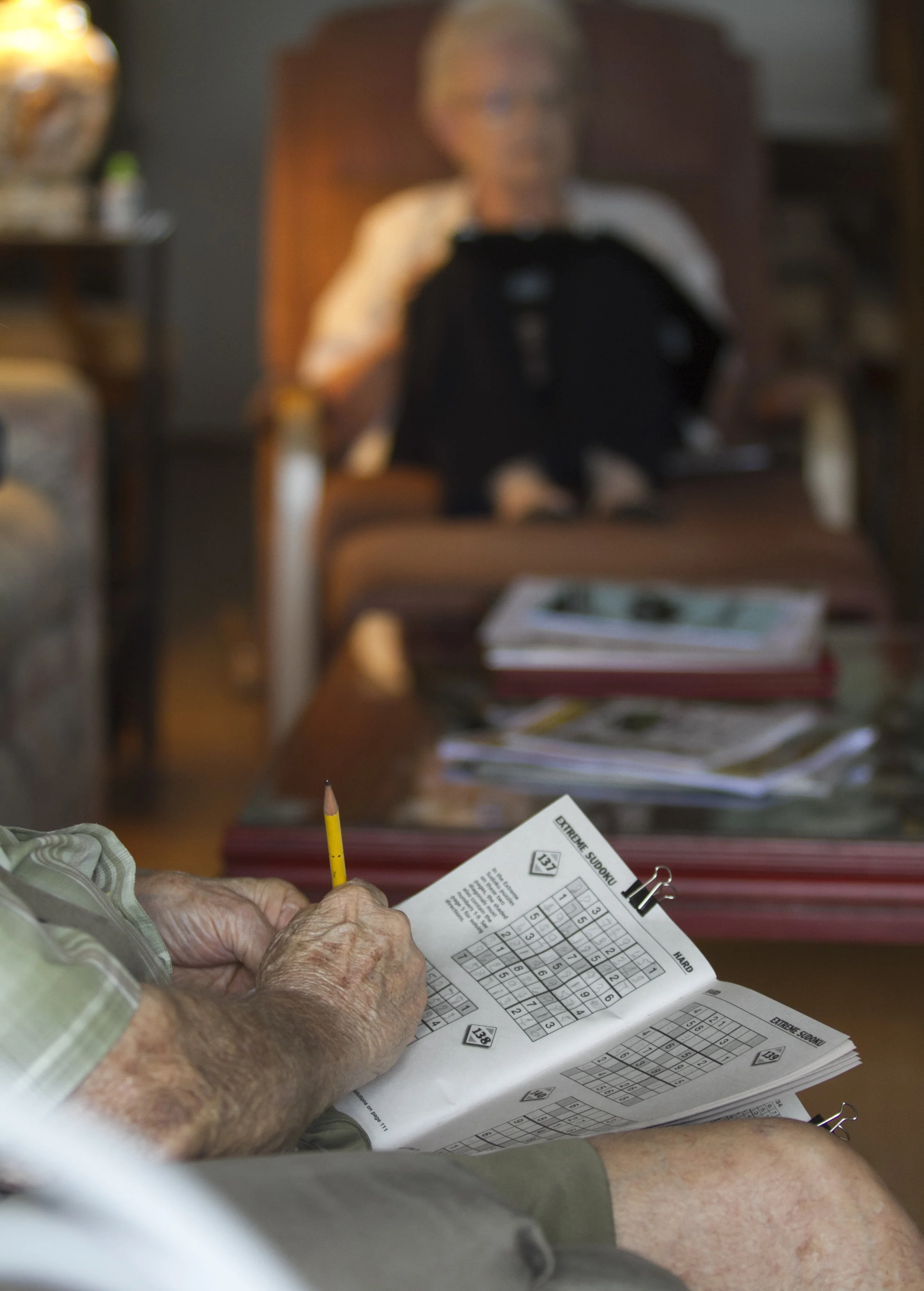  After eating their lunch, Kate and Joe Pre-Genzer sit together watching TV. Joe does sudoku while Kate checks email on her tablet. 