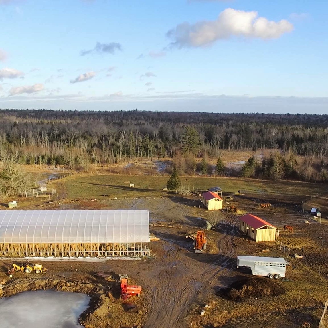 Bird’s Eye View The two red roofed buildings are the horse sheds. The large hoop structure is our hay storage/riding ring combo. And yeah, that pond is solid ice still, despite the melting mud in the road…
