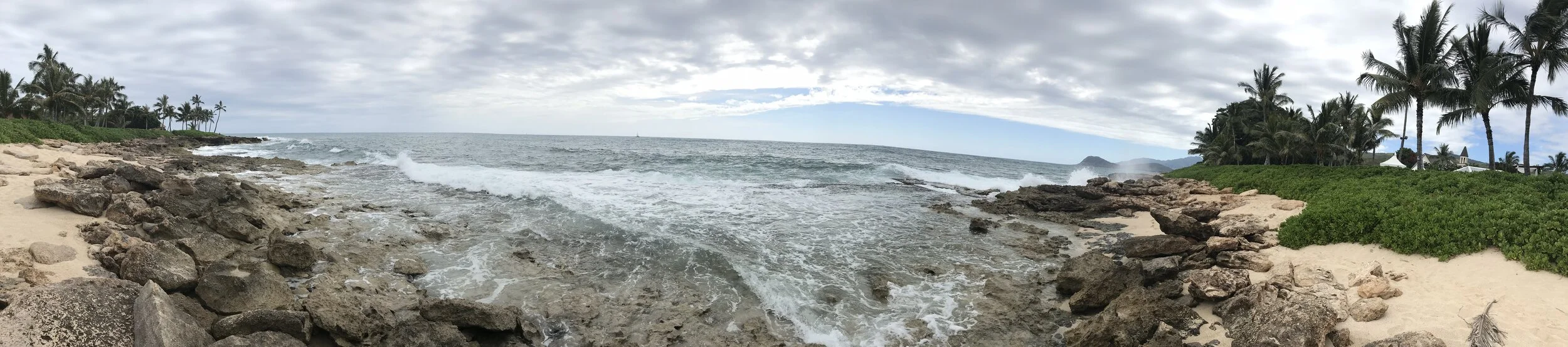 Private cove and Hawaiian mountain ranges behind the ceremony grassy space.