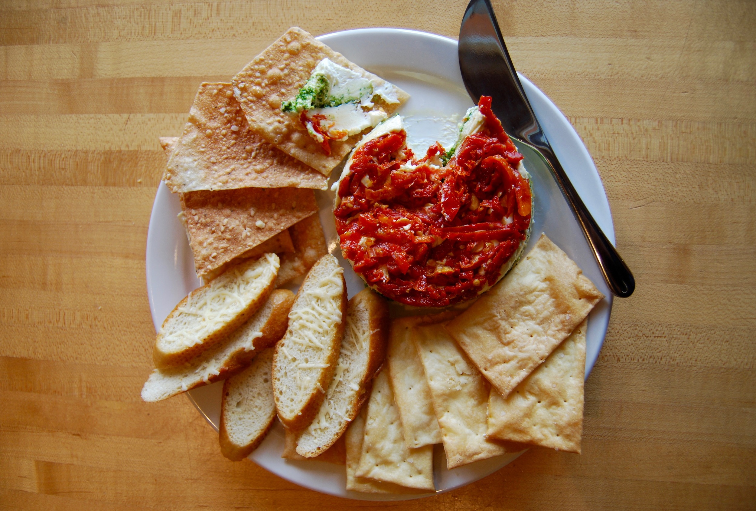 Clockwise from the top-left: Sundried Tomato Basil Pesto Torta with Cream Crackers, Crostini, and Sesame Crisps Photograph by Lauren Philips