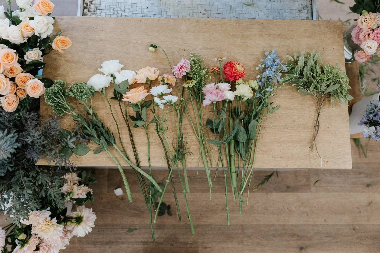 Various colorful fresh flowers arranged on a wooden table.