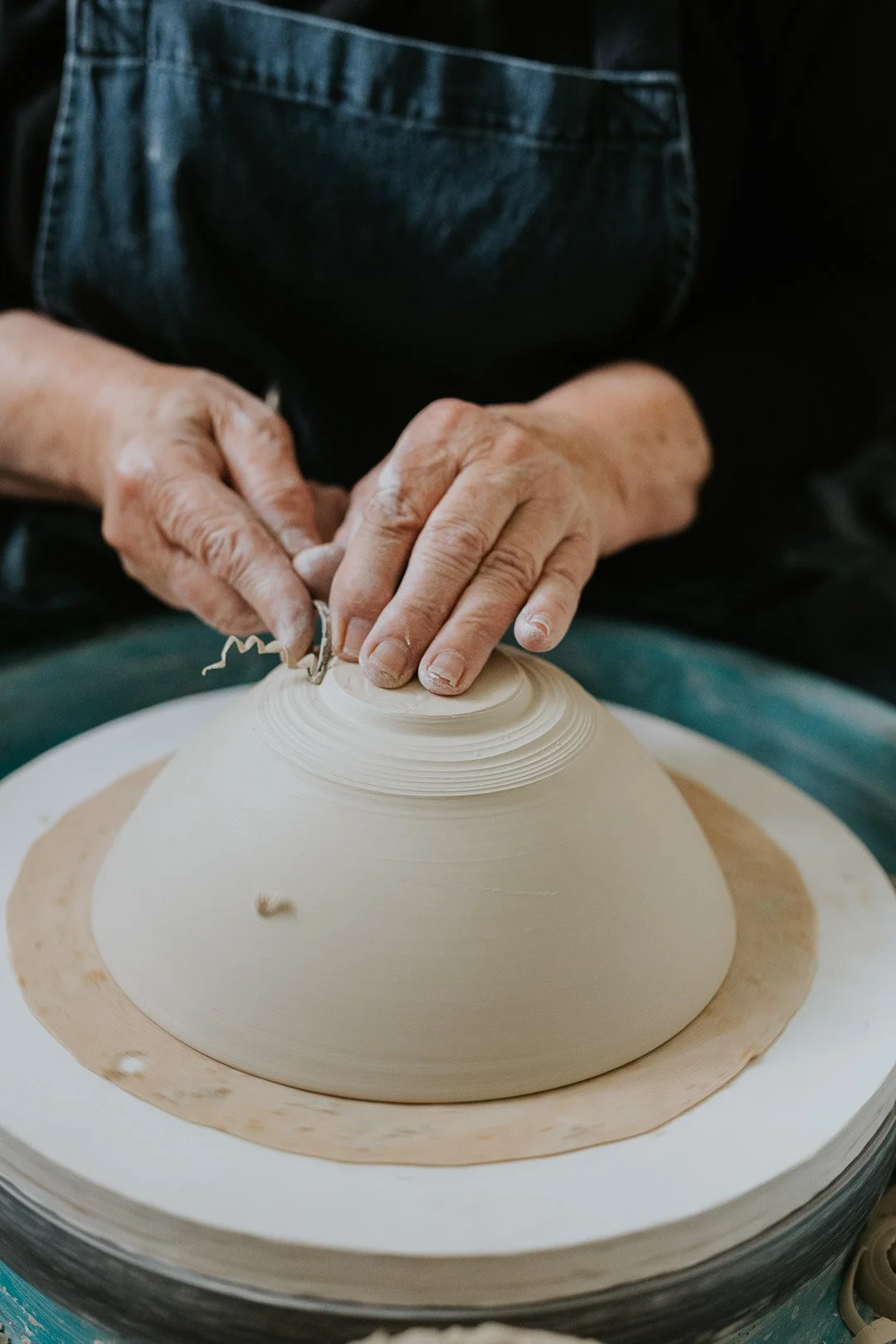 Close-up of a person shaping a ceramic bowl on a pottery wheel with their hands.
