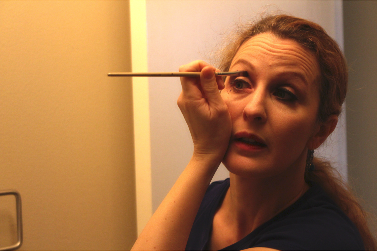 Amara applies eye shadow in her personal studio’s bathroom.