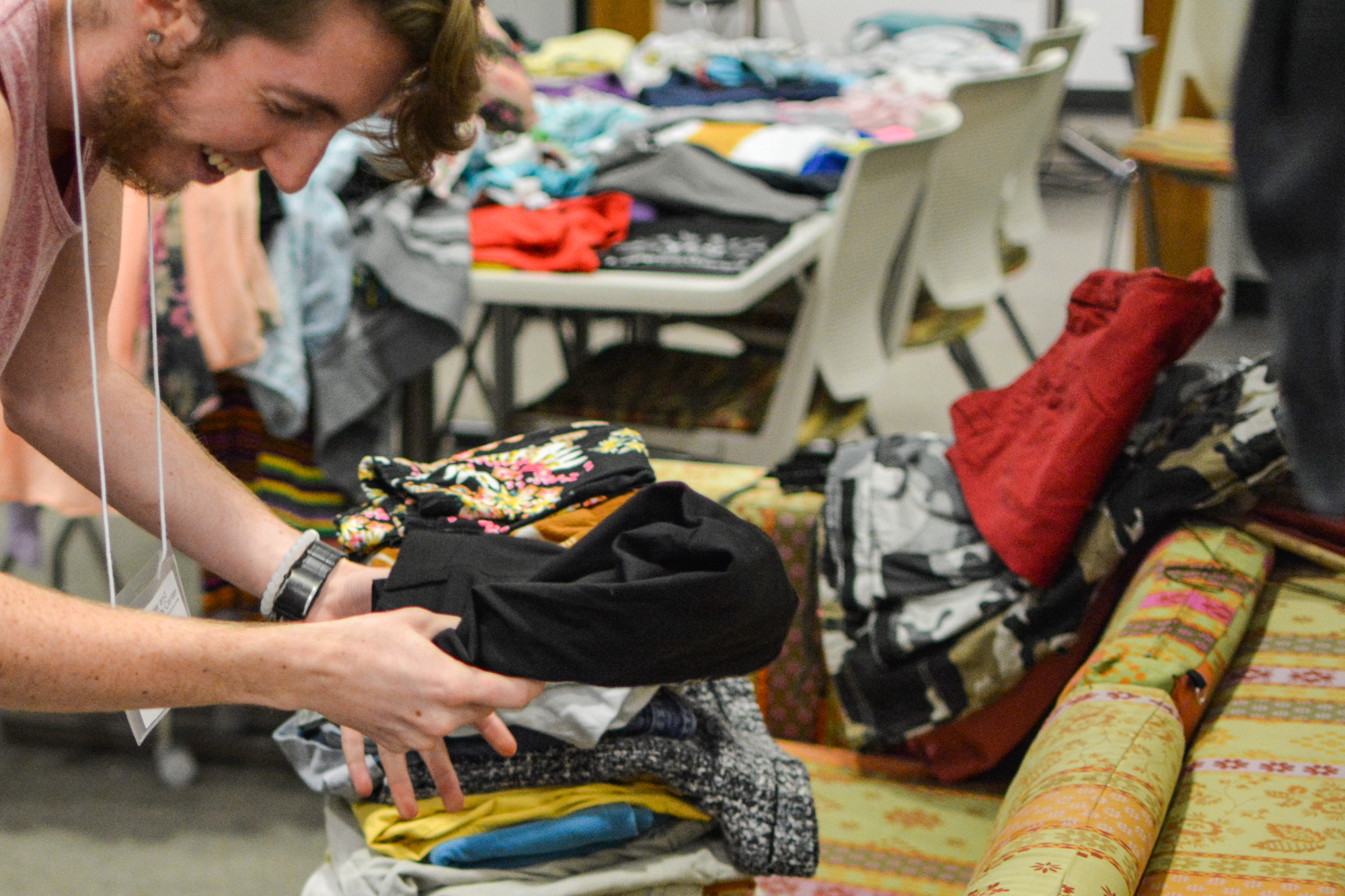 A student worker is all smiles at the Gender and Sexuality Center as he helps put leftover clothes into piles.