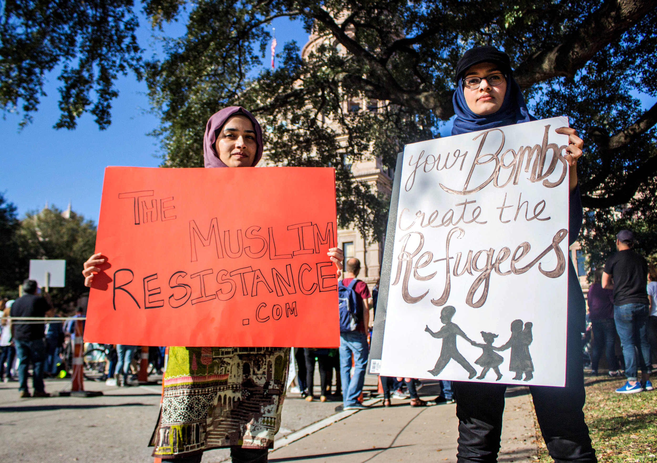 Zainab Haider, right, holds a sign that says, "Your bombs create the refugees" and Tasbiha Batool, left, holds a sign that says, "The Muslim Resistance .com" near the Capitol.