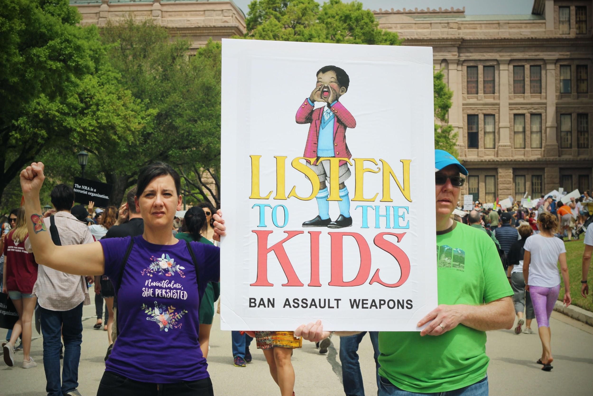 Standing in front of the capitol, a couple resists by holding up their sign.