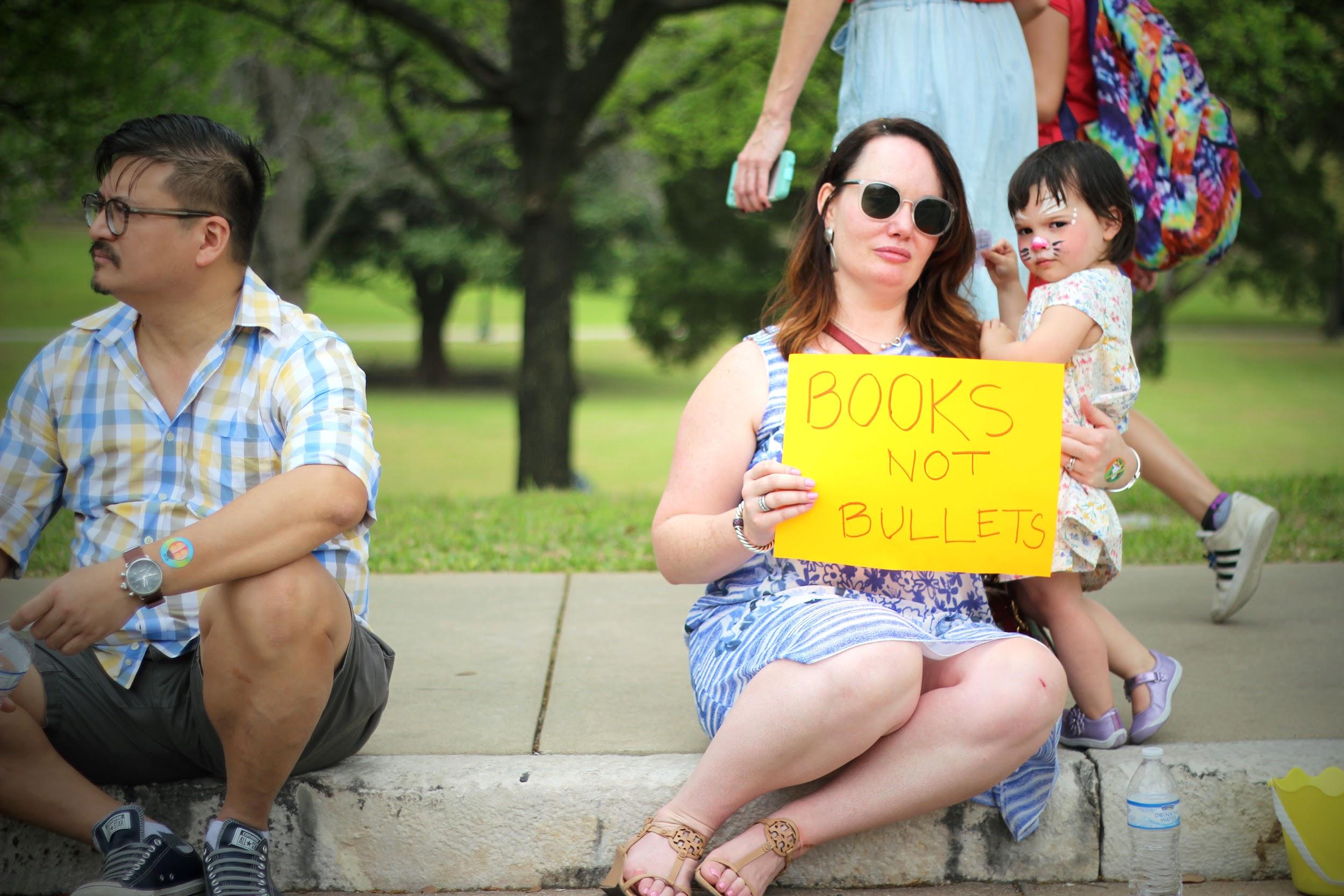 Sitting on a curb near the Capitol, a mother and her daughter show their sign.