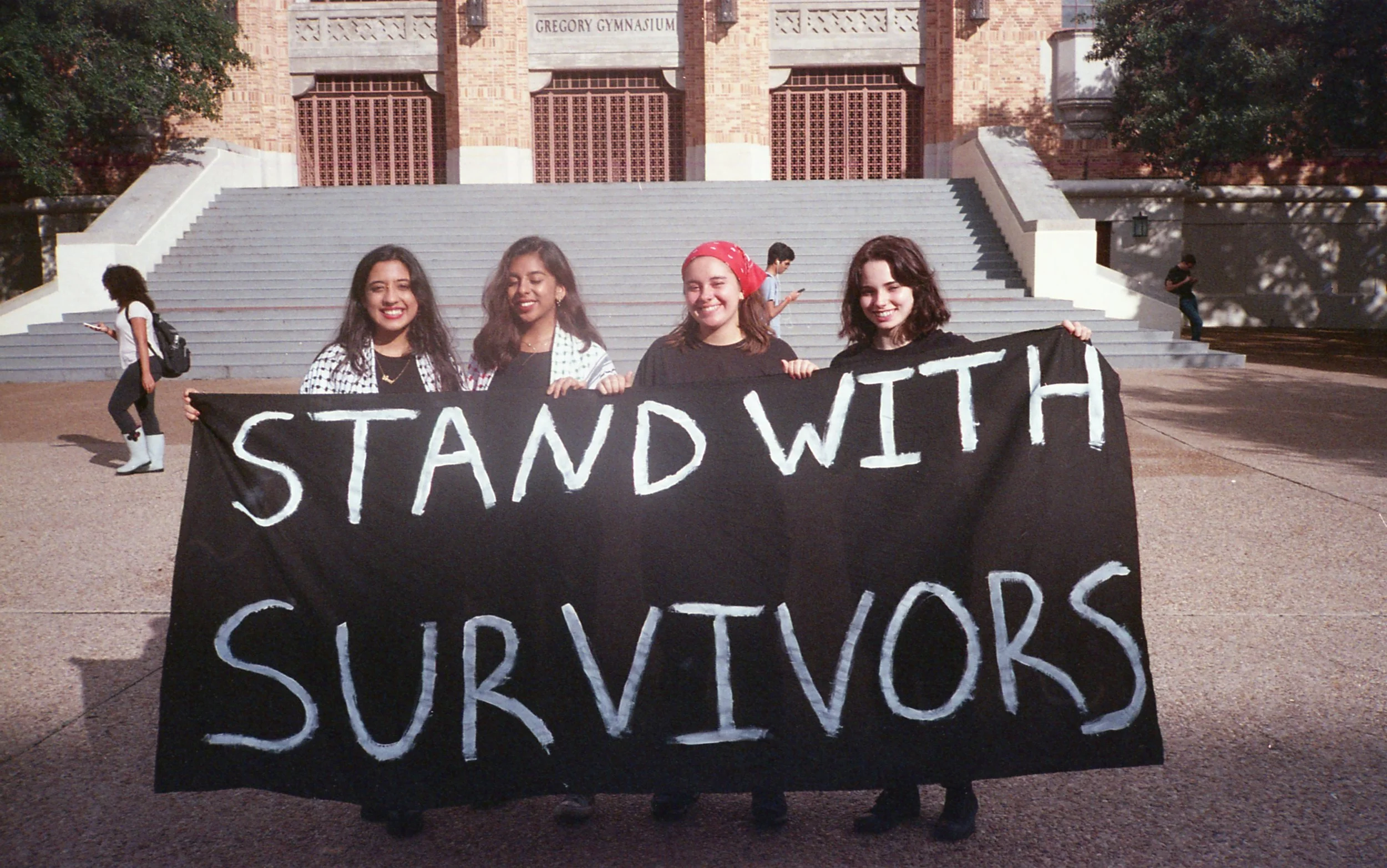 The organizers of the event, Sonya, Rimsha, Angel and Sarah pose for a photo with a Stand with Survivors sign
