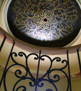 In this mid-production shot of a rotunda style foyer, you can see, we incorporated a ceiling pattern that reflected the ironwork on the stair rail spindles. The ceiling was finished in a chocolate Venetian Plaster and embossed with a metallic gold Venetian Plaster.