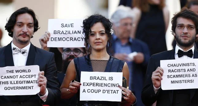 Brazilian actress Maeve Jinkings holds a sign reading 'Brazil is experiencing a coup d'etat' as she leaves after the screening of 'Aquarius' during the 69th annual Cannes Film Festival, in Cannes, France, 17 May 2016. Image credit: Daily Sabah .