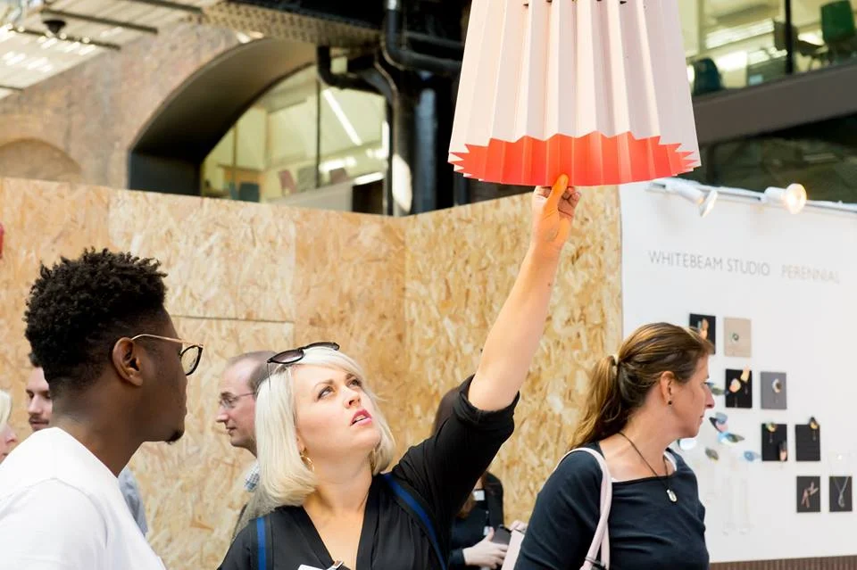 Customers admiring the Twin Tone Lampshade at the Little Greene stall. Photograph for Design Junction by Ruth Ward .