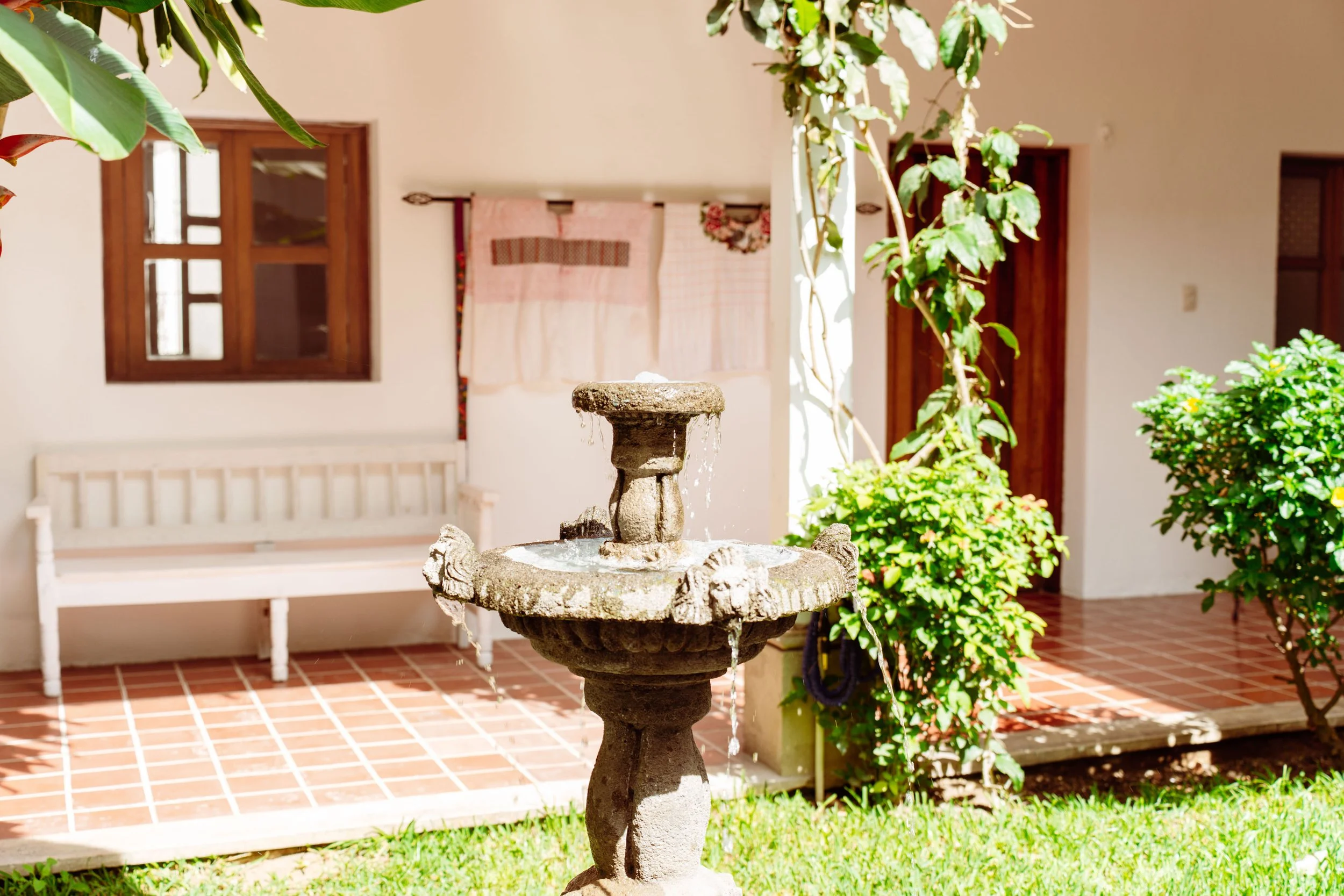 Patio interior de una propiedad residencial en Antigua Guatemala, con fuente, jardín y arquitectura colonial.