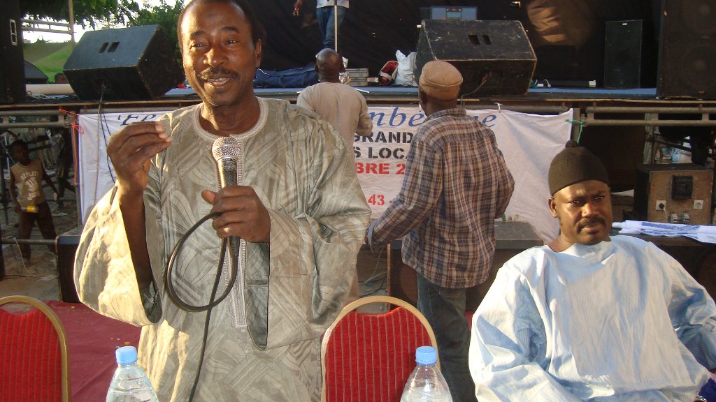 Lamine donne son discours sur la santé de la communauté lors de la conférence . Sur sa gauche se trouve le guide religieux et chercheur en médecine traditionnelle.