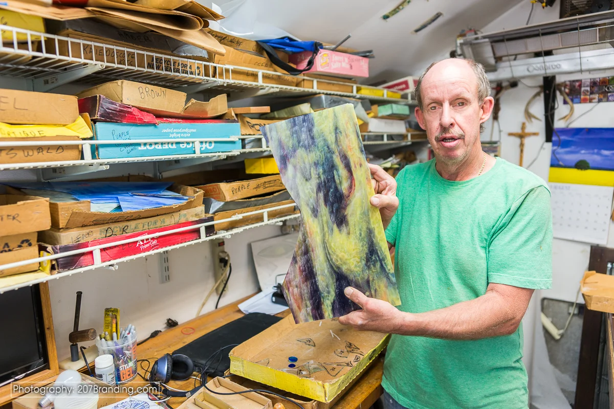 Denver Stained Glass Artist in Green Shirt holding a piece of raw stained glass