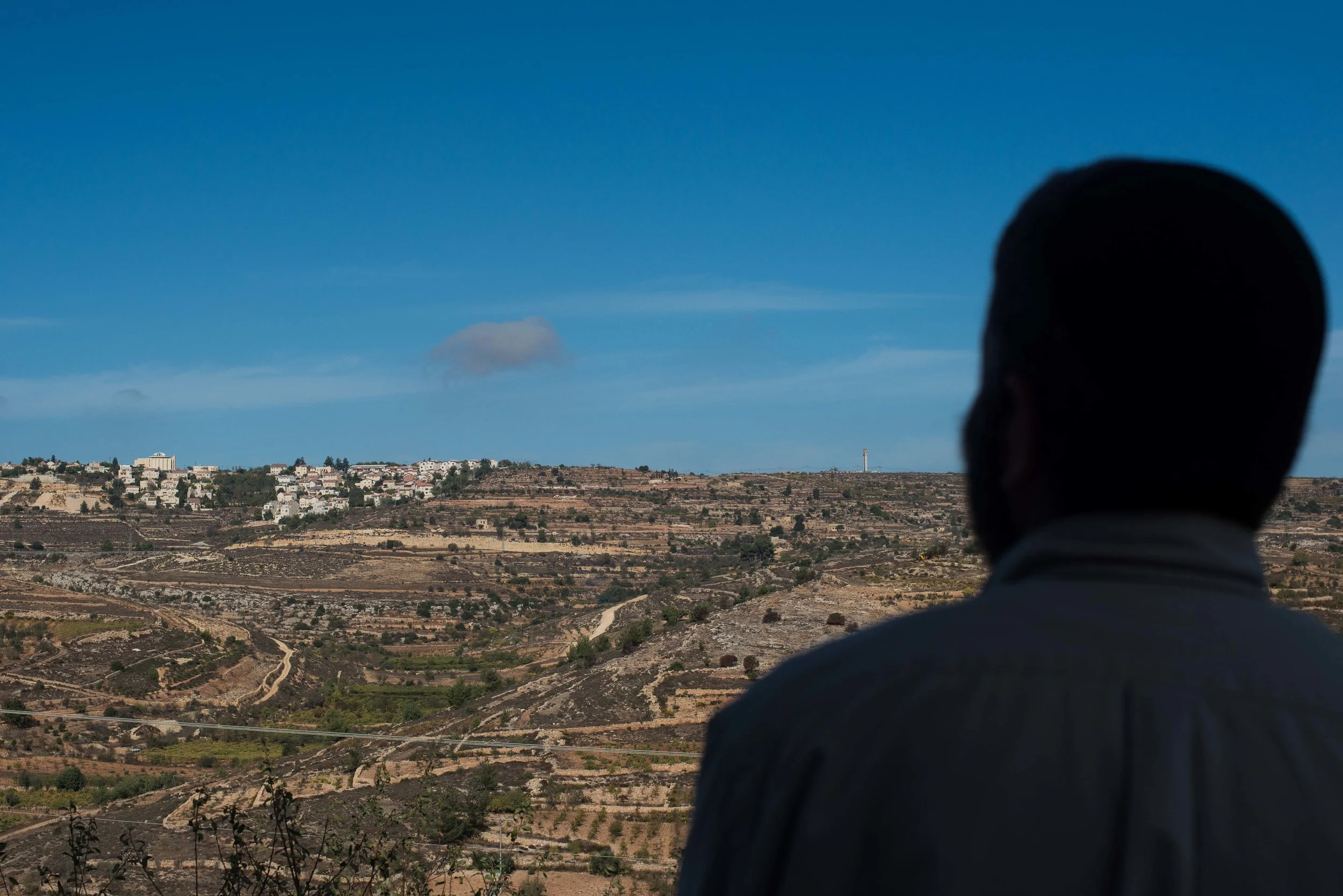 Daniel Zahavi-Asa looks off his balcony onto a neighboring illegal settlement atop a hillside across the valley known is Hebrew as Gush Etzion in the West Bank, Palestine.
