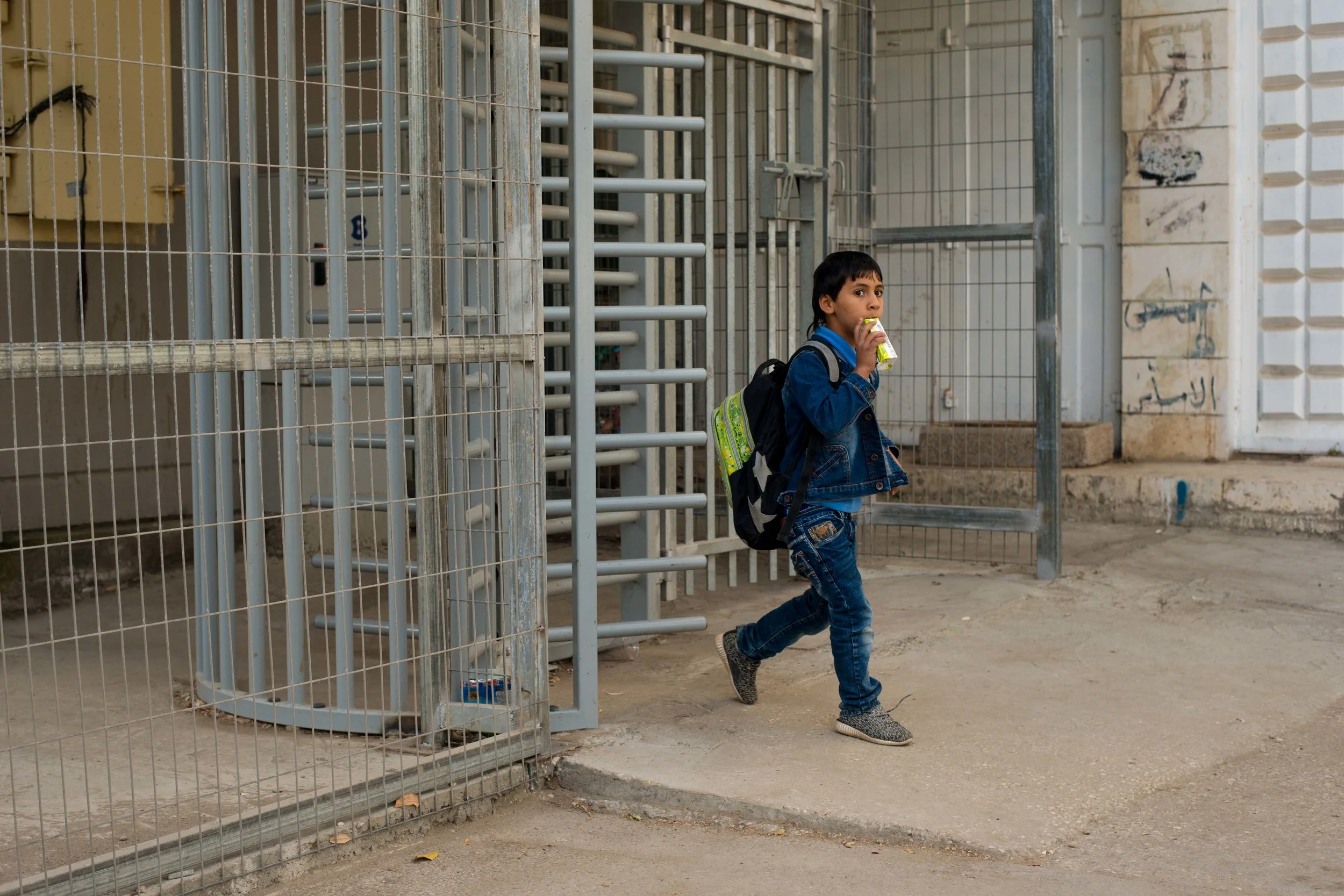 A Palestinian boy walking through a checkpoint on his way to school. Old City Hebron (H2), West Bank, Palestine.