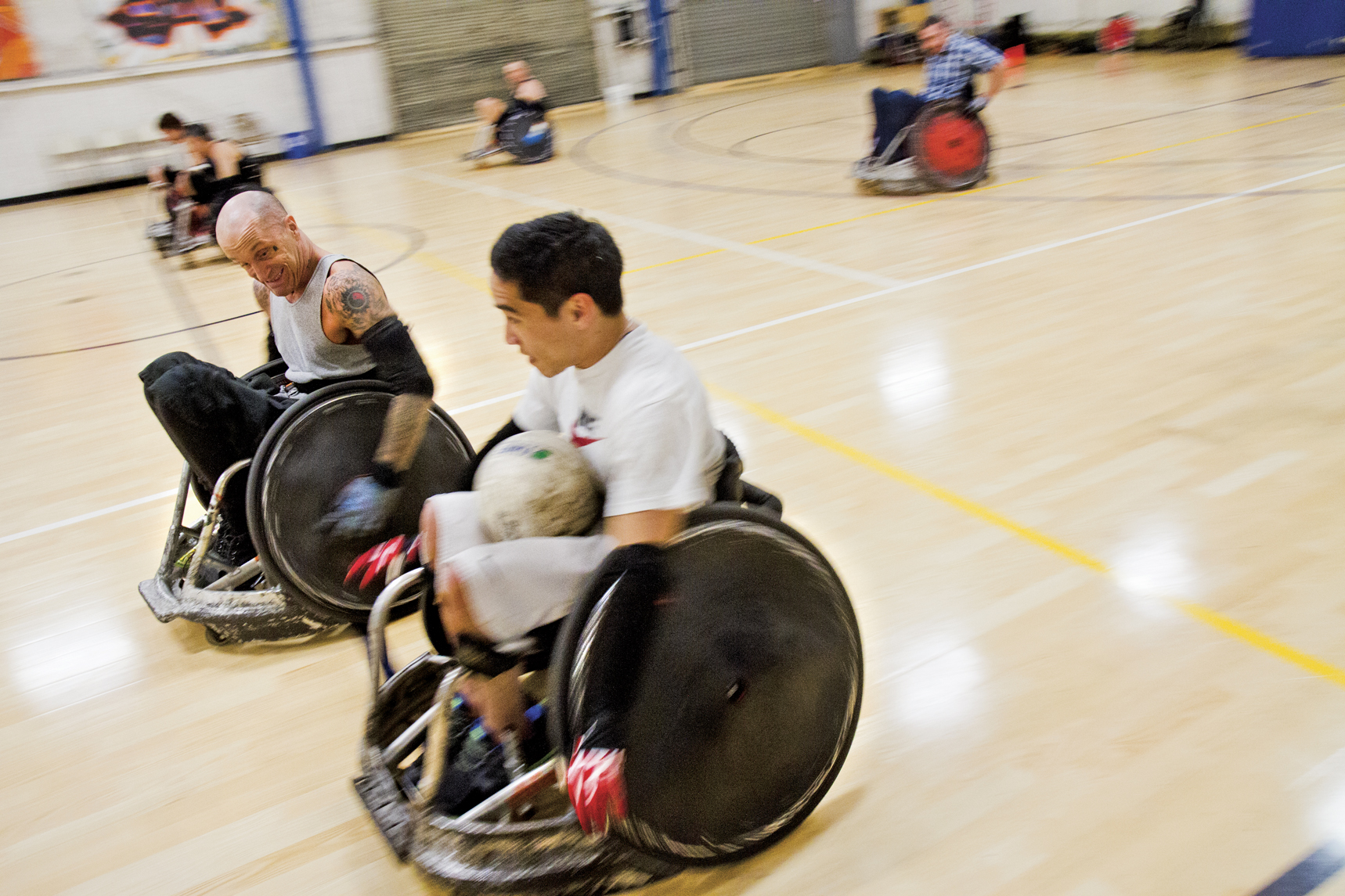 Paraplegic rugby player Scott Pope tries to get the ball from Steven Toyoji during a scrimmage at the Riekes Center.