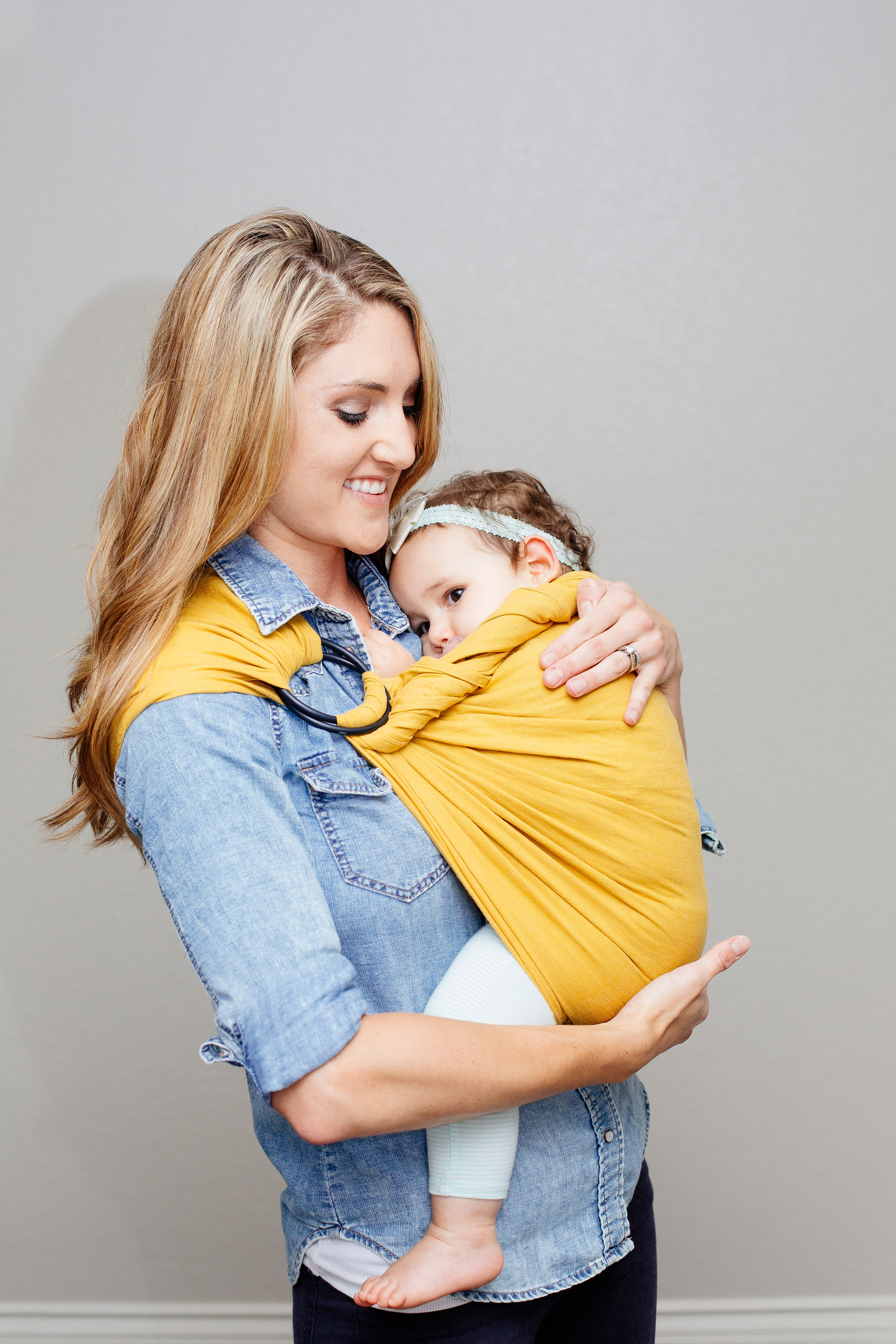 Newborn twist: Once you have the sling secure twist the tail of the sling and pull across the top rail and tuck in. If there is additional fabric on the top rail you can fold that down over your twisted tail. This will provide additional neck support for newborns and infants with little neck strength.