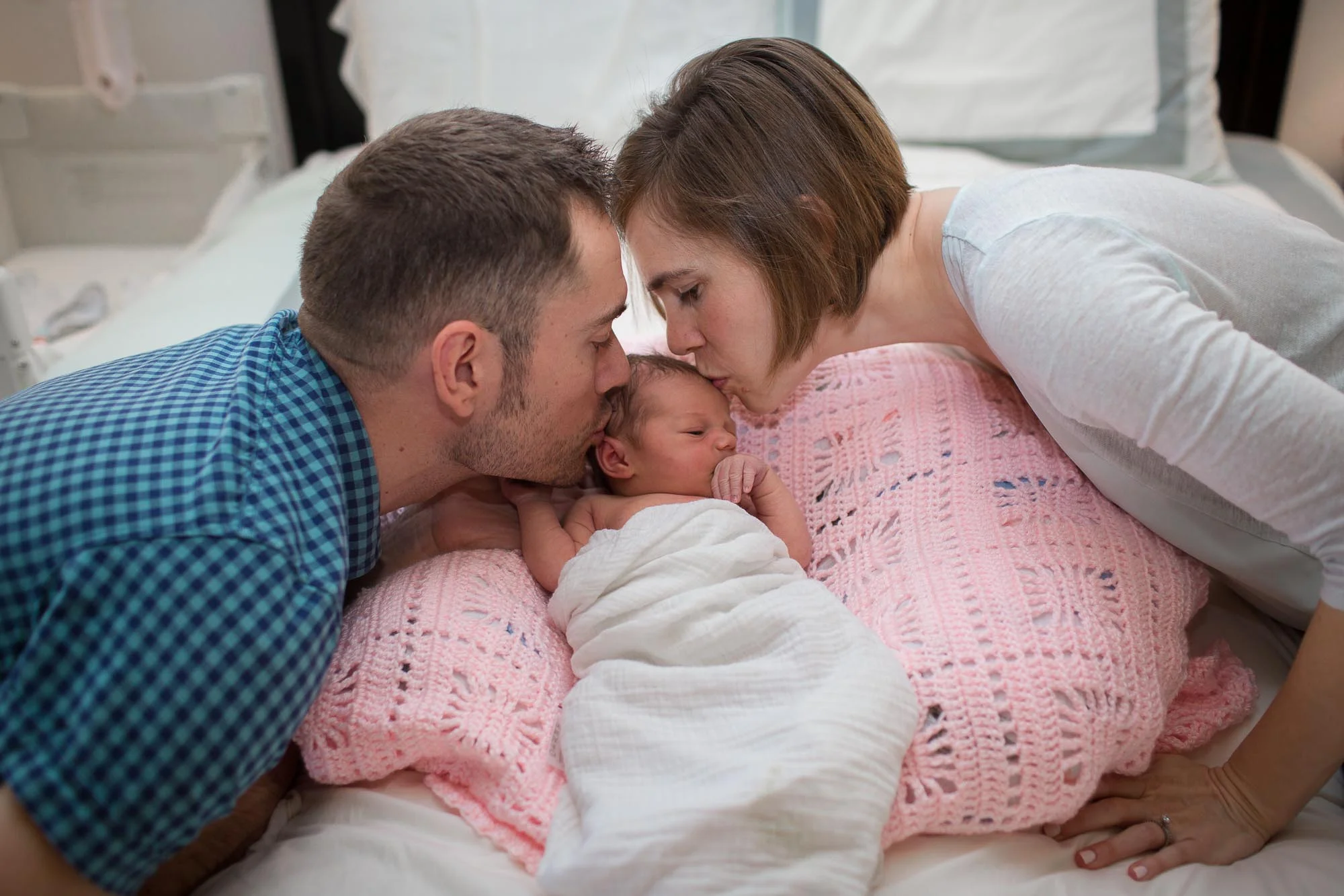 Mommy and Daddy kissing baby. Austin in-home baby photographer.