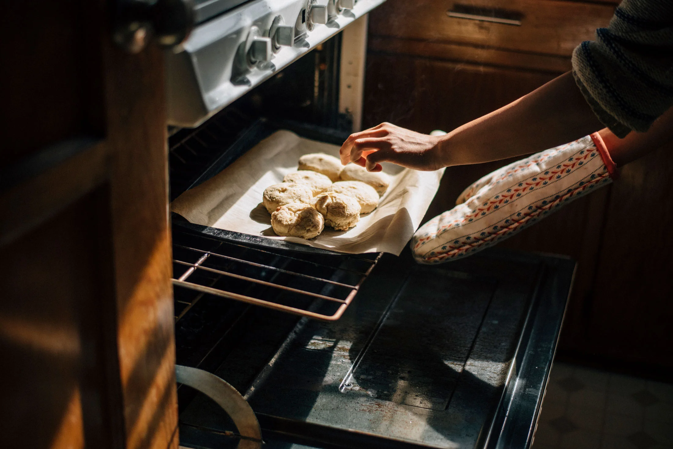 Hands taking biscuits out of oven