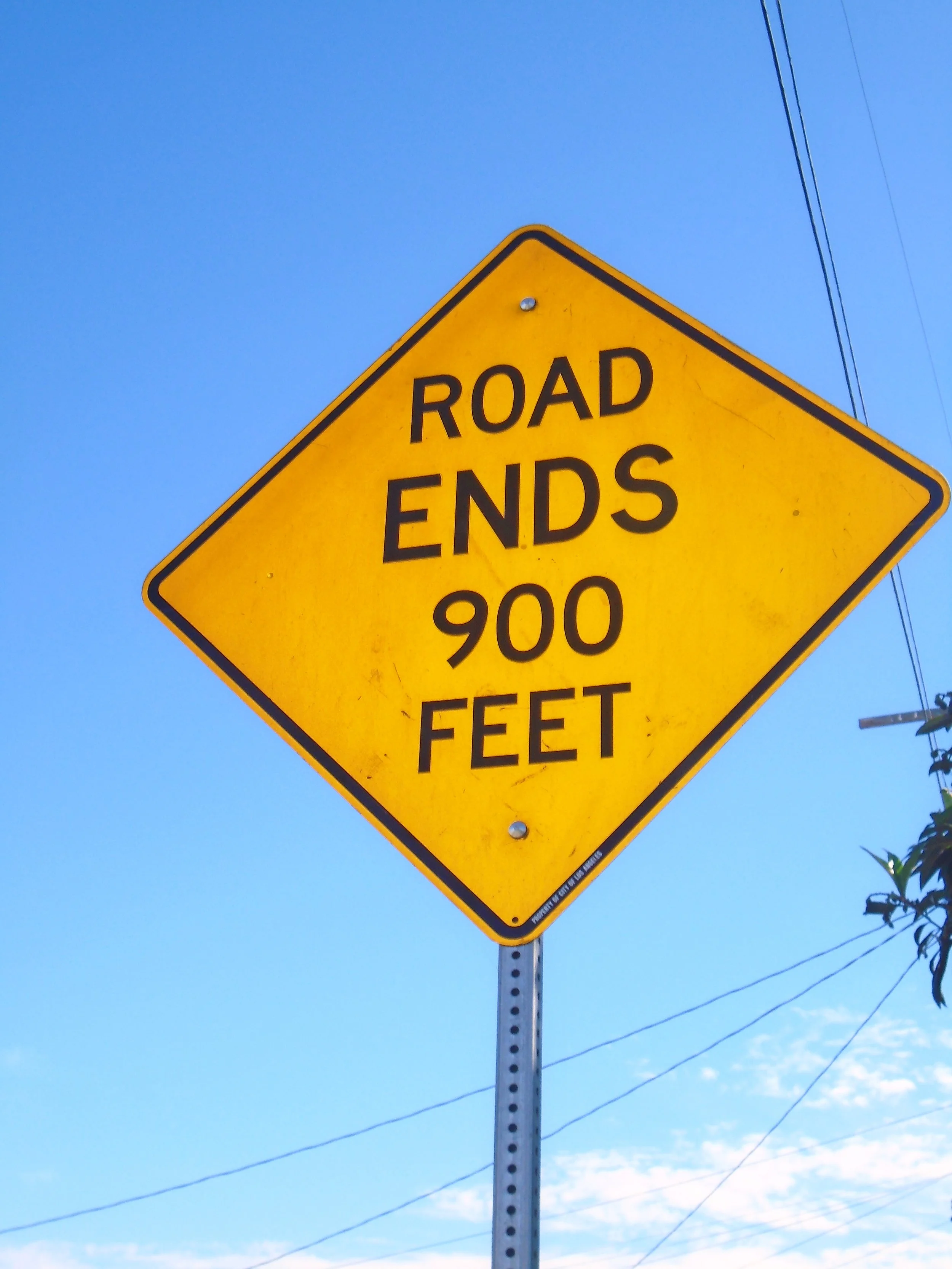 Yellow diamond-shaped road sign indicating the end of the roadway at 900 feet.