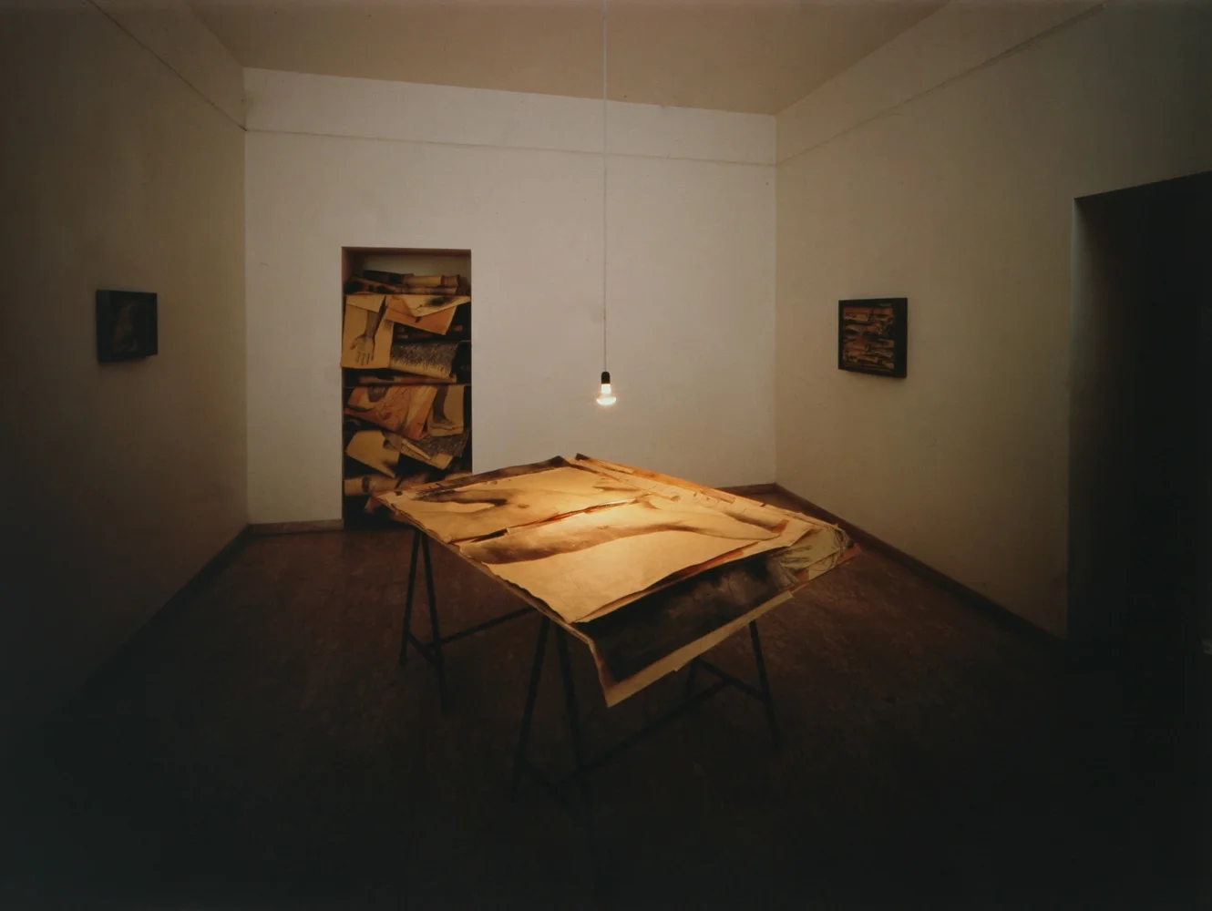 installazione, le stanze dell'arte tullio pironti, piazza dante, napoli 2002 Vincenzo Trione Ci troviamo in un altro atelier, adesso. Manzo vi ha posto al centro una scrivania, irradiata da una luce bassa, ricoperta di carte sfregiate, tagliate, sporche di aloni di matita, occupate da corpi infranti. Alle pareti, teche di ferro brunito, con fasci di pagine strappate, che sono iscritti all’interno di enigmatiche armonie. In fondo, in una sorta di ripostiglio, ancora pezzi di carta… Manzo contiene i tempi della propria narrazione. Altera il “carattere” della sua raffigurazione. Agendo liberamente su materiali eterogenei, destruttura la centralità del soggetto; incastona e dispone in maniera non casuale una quantità di fogli appiattiti l’uno sull’altro: in questo magma, l’intero ricompare protetto. L’installazione di Manzo è fondata sull’incontro tra molteplicità e unità. All’apparenza, vediamo tante “tessere” indipendenti. In realtà, ci troviamo dinanzi a un’opera scandita dalla presenza di tanti frammenti impazziti, percorsi da ferite. Queste schegge sono poste in un assemblaggio, che si sottrae al nostro sguardo. Scorgiamo solo tasselli di un mosaico senza centro.