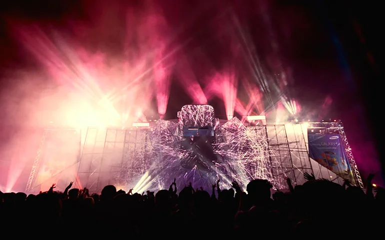 Concert stage with colorful lights and audience at night.