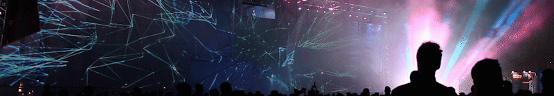 Crowd at a concert with colorful lights and laser projections.