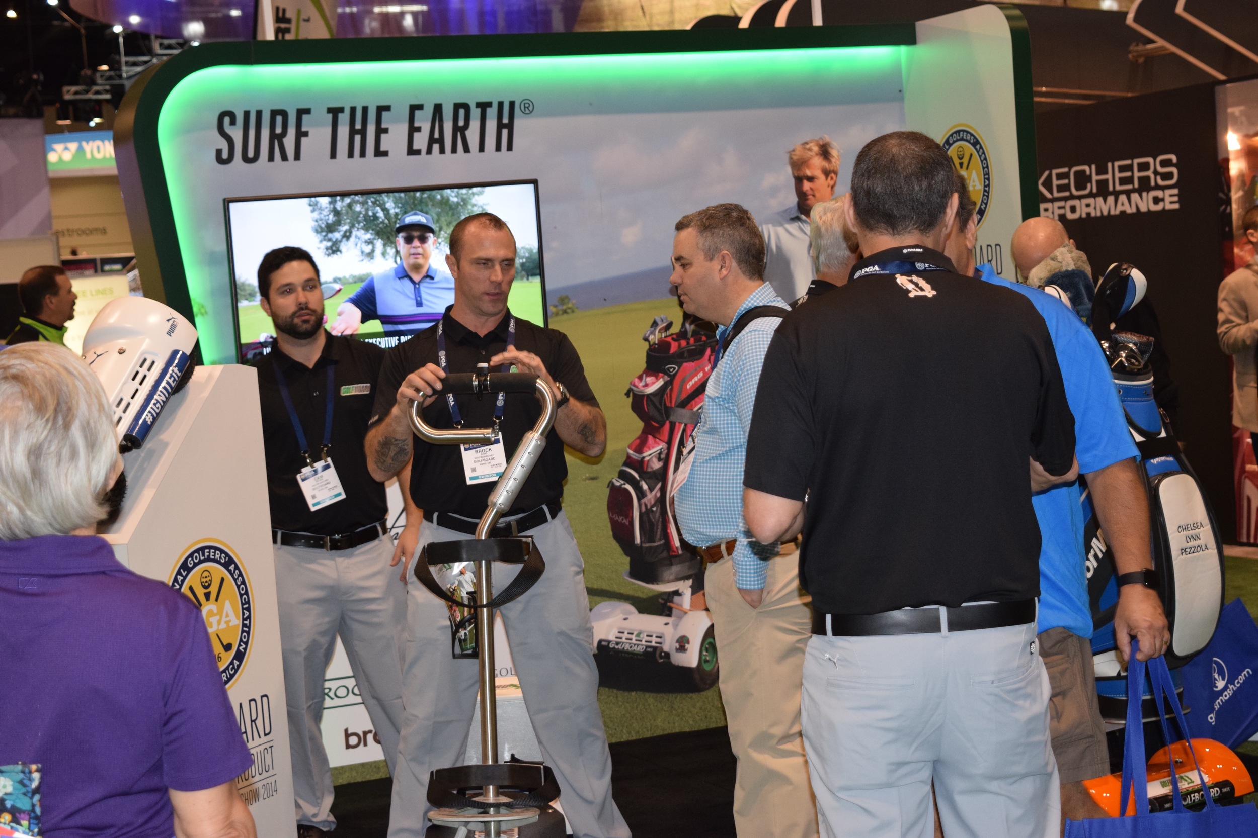 Brock Sabo demonstrates the GolfBoard to a captivated show patron while Cam Petriw looks on.