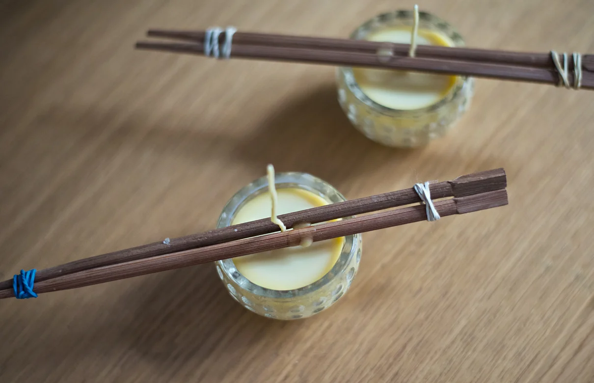 Nous avons trempé les mèches dans la cire pour les durcir, puis nous les avons collées au fond des bougeoirs, fixées en haut pour qu'elles tiennent droit, avant de verser doucement la cire fondue.