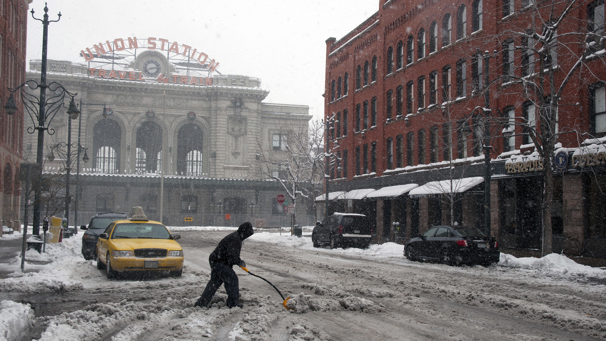  A man clears snow on Denver's 17th Street during a blizzard. By the time the snow stopped, nearly a foot and a half of snow blanketed the city. 