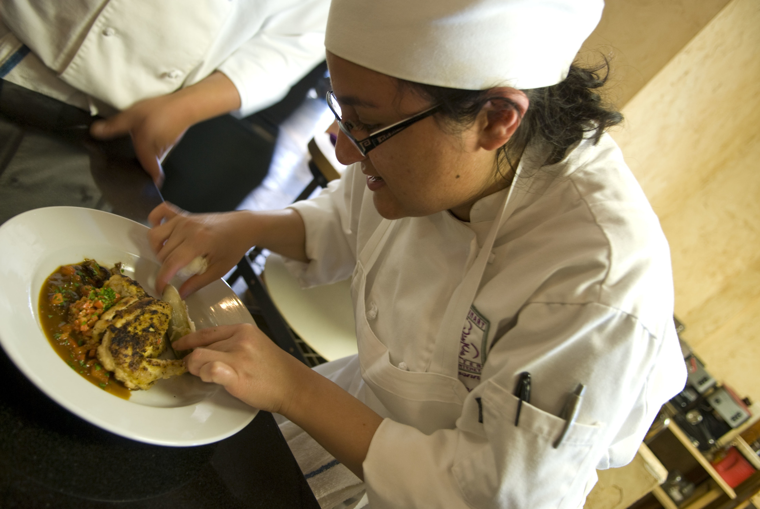 Student Nina Justamonte of the Culinary Centre of Monterey adds the finishing touches to a game hen on 20 March 2008.