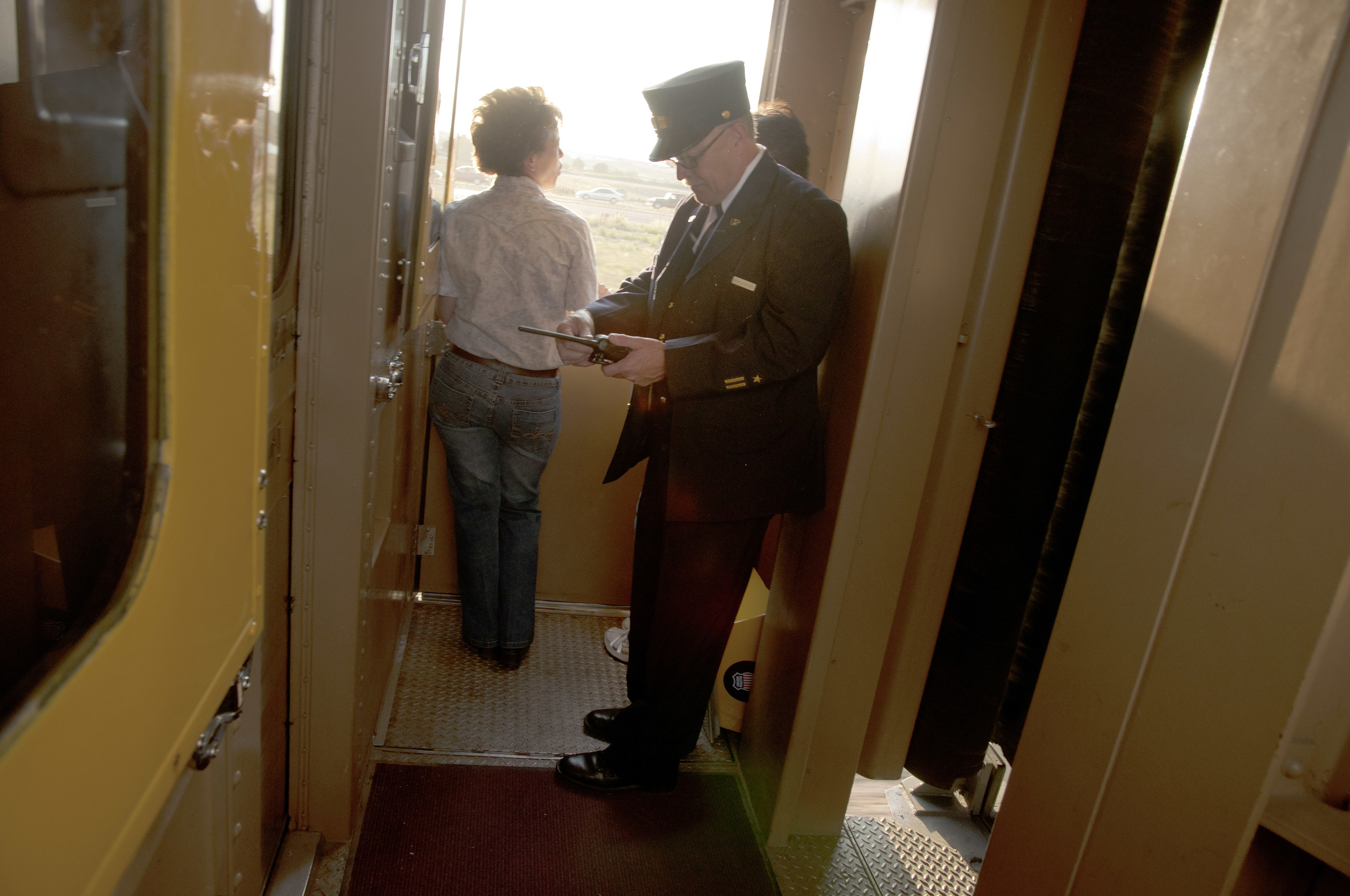 A Union Pacific conductor checks his radio momentarily in the vestibule aboard the Denver Post's Cheyenne Frontier Days passenger special train as it chugs across northern Colorado. The vintage carriages were brought in specially for this run, and d