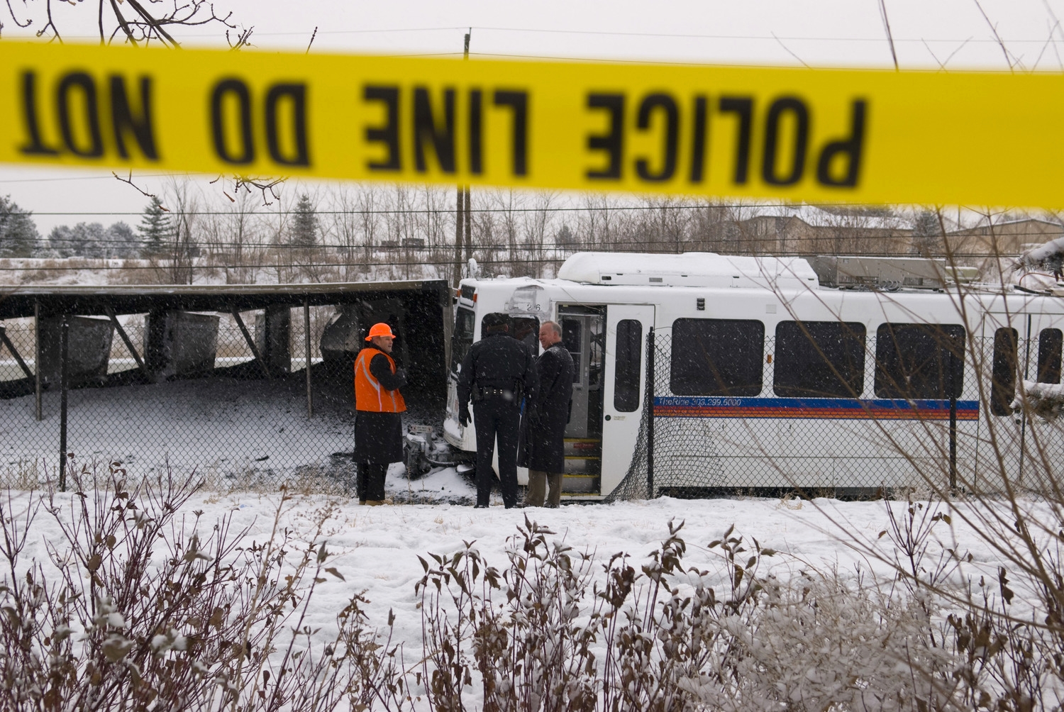 Littleton Police investigators and Union Pacific workers survey the carnage after an RTD light rail train collided with an overturned Union Pacific coal train in Littleton on 11 December 2007.