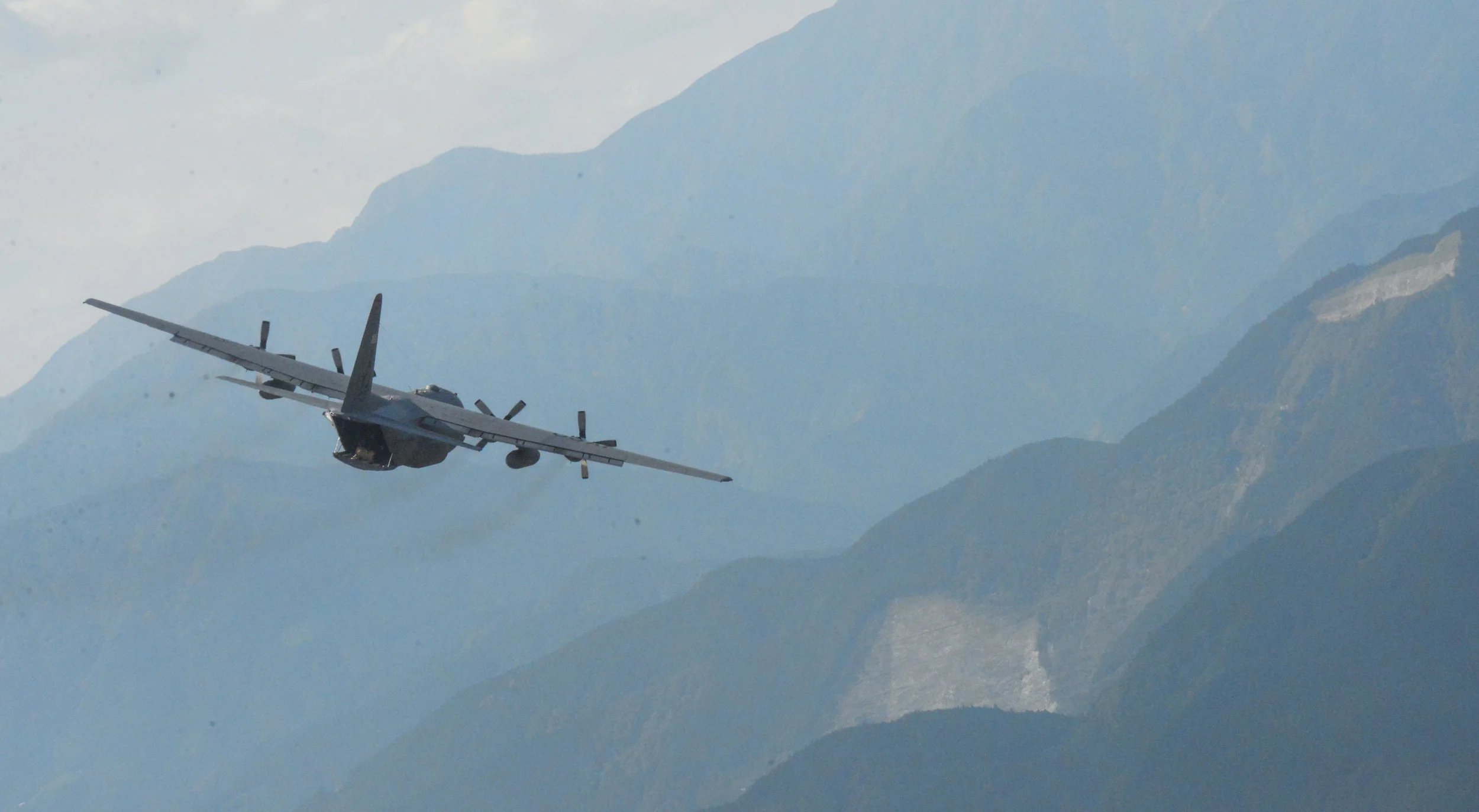 A C-130 Hercules flies over a mountainous region of Japan, Oct. 14, 2015. Performing regular in-flight operations gives all related operations personnel real -world experience to stay prepared for contingency situations. (U.S. Air Force photo by Airman 1st Class Elizabeth Baker/Released)