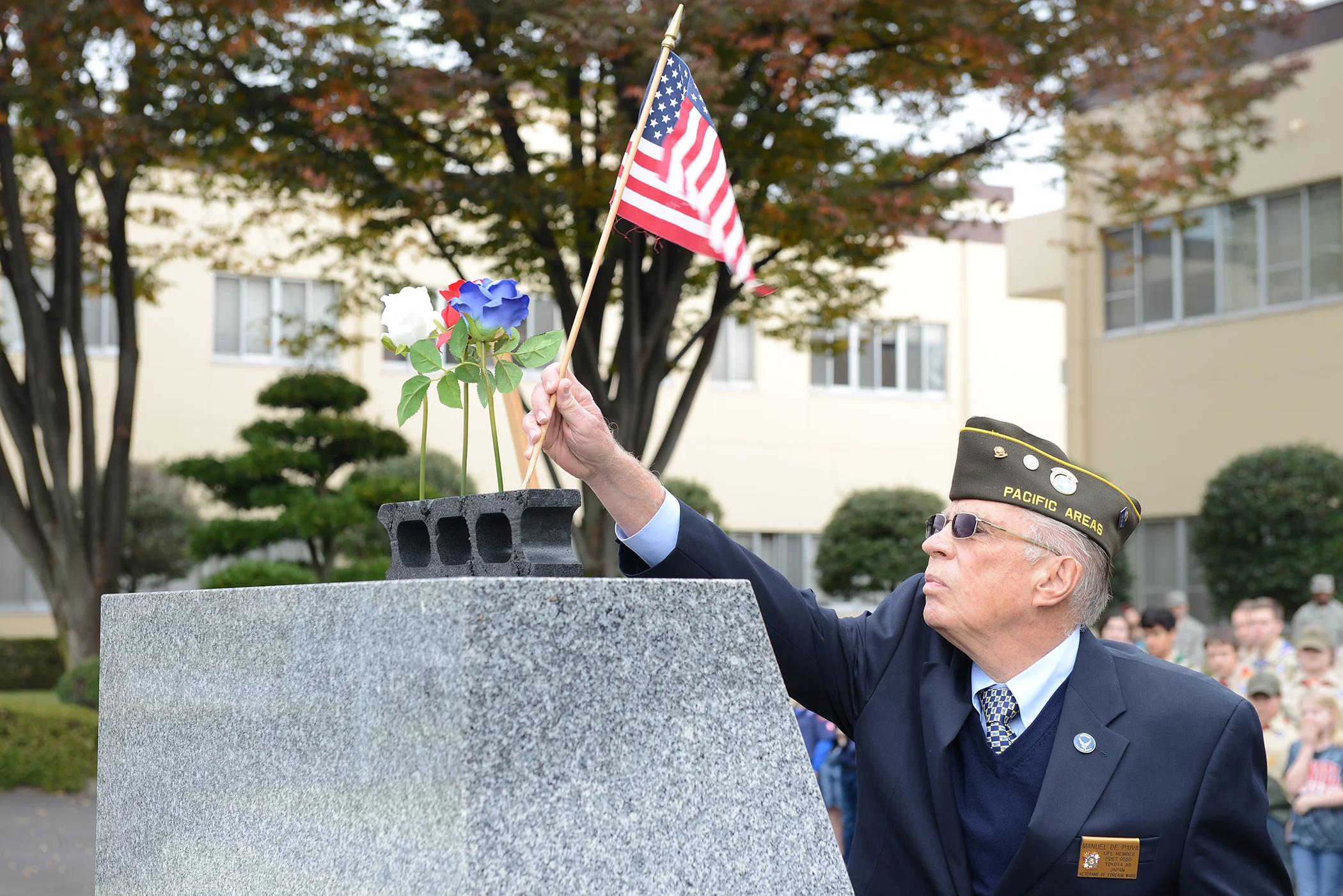 A member of the Veterans of Foreign Wars places an American flag on a monument during the three flower ceremony at Yokota Air Base, Japan, Nov. 11, 2015. The three flowers each have a different meaning: The red rose represents those who have died in defense of their country, the white celebrates future service members and the blue immortalizes the deeds of Soldiers, Sailors, Airmen and Marines. (U.S. Air Force photo by Senior Airman David C. Danford/Released)