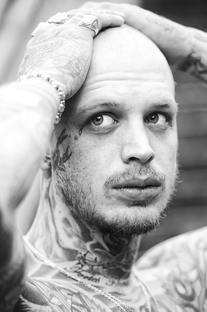 black and white portrait photo of a heavily tattooed man