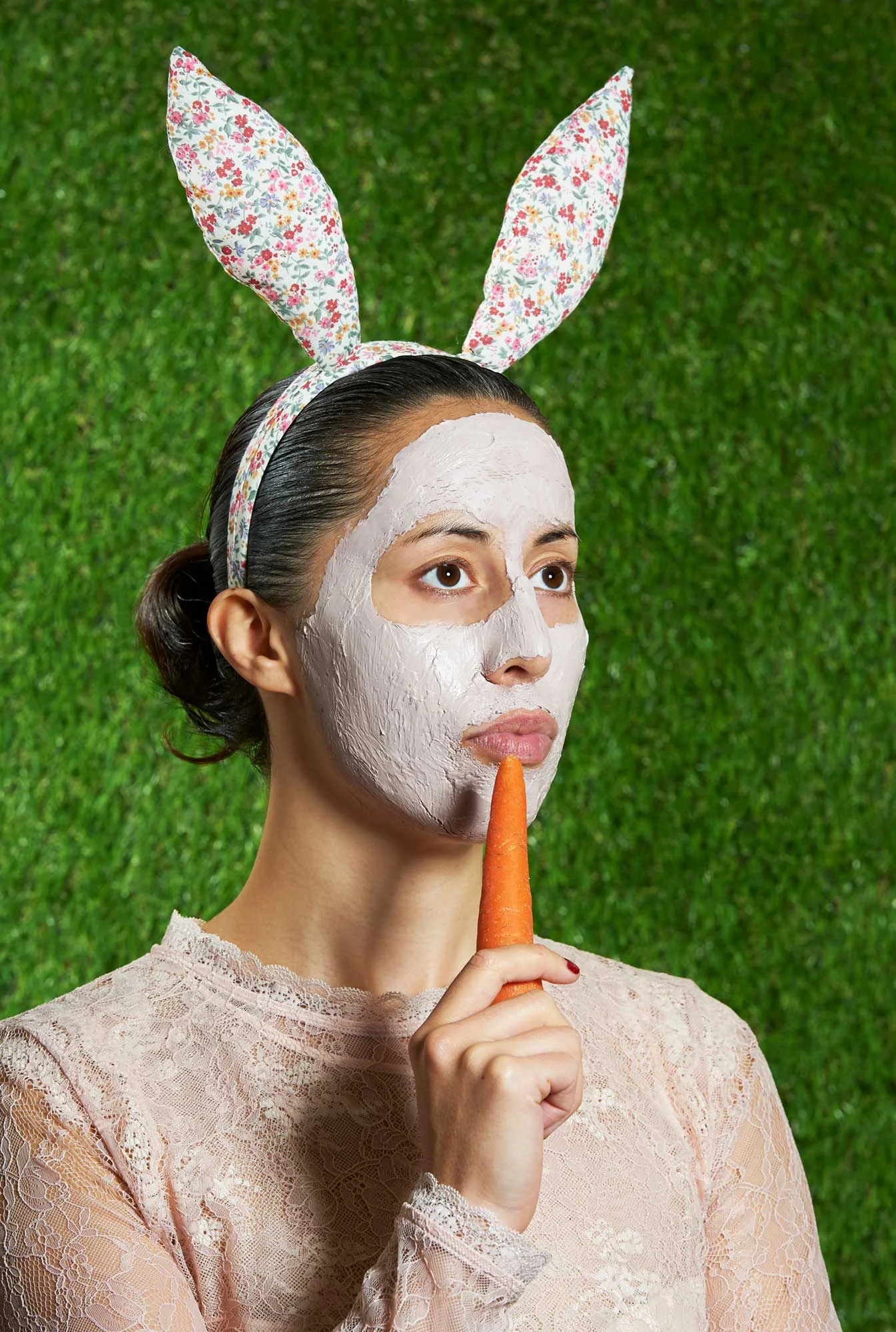 Portrait of a woman wearing bunny ears, holding a carrot